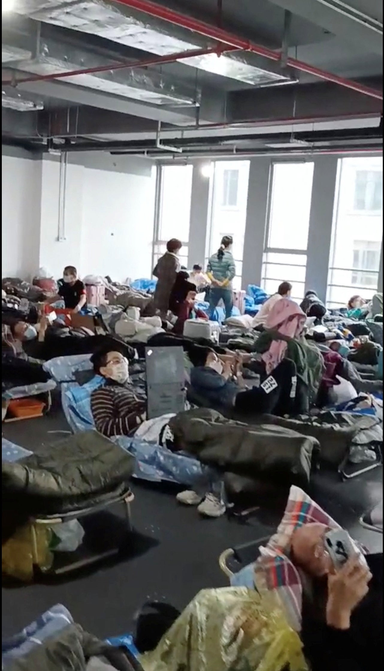 A man uses a laptop while people rest at a quarantine centre near Linkong Skate Park in Changning district, Shanghai