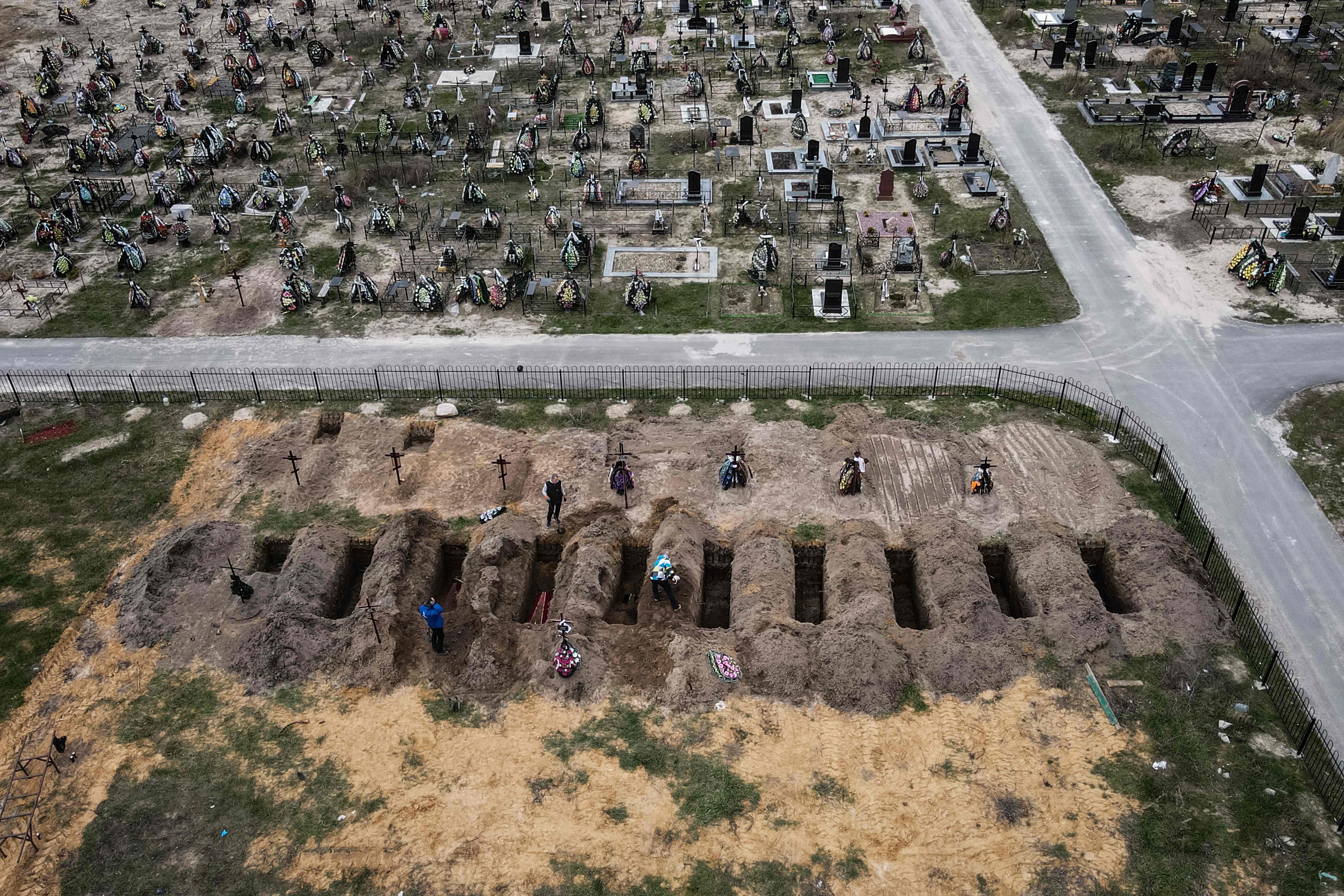 An aerial picture taken on April 18, 2022 shows coffins being buried during a funeral ceremony at a cemetery in Bucha