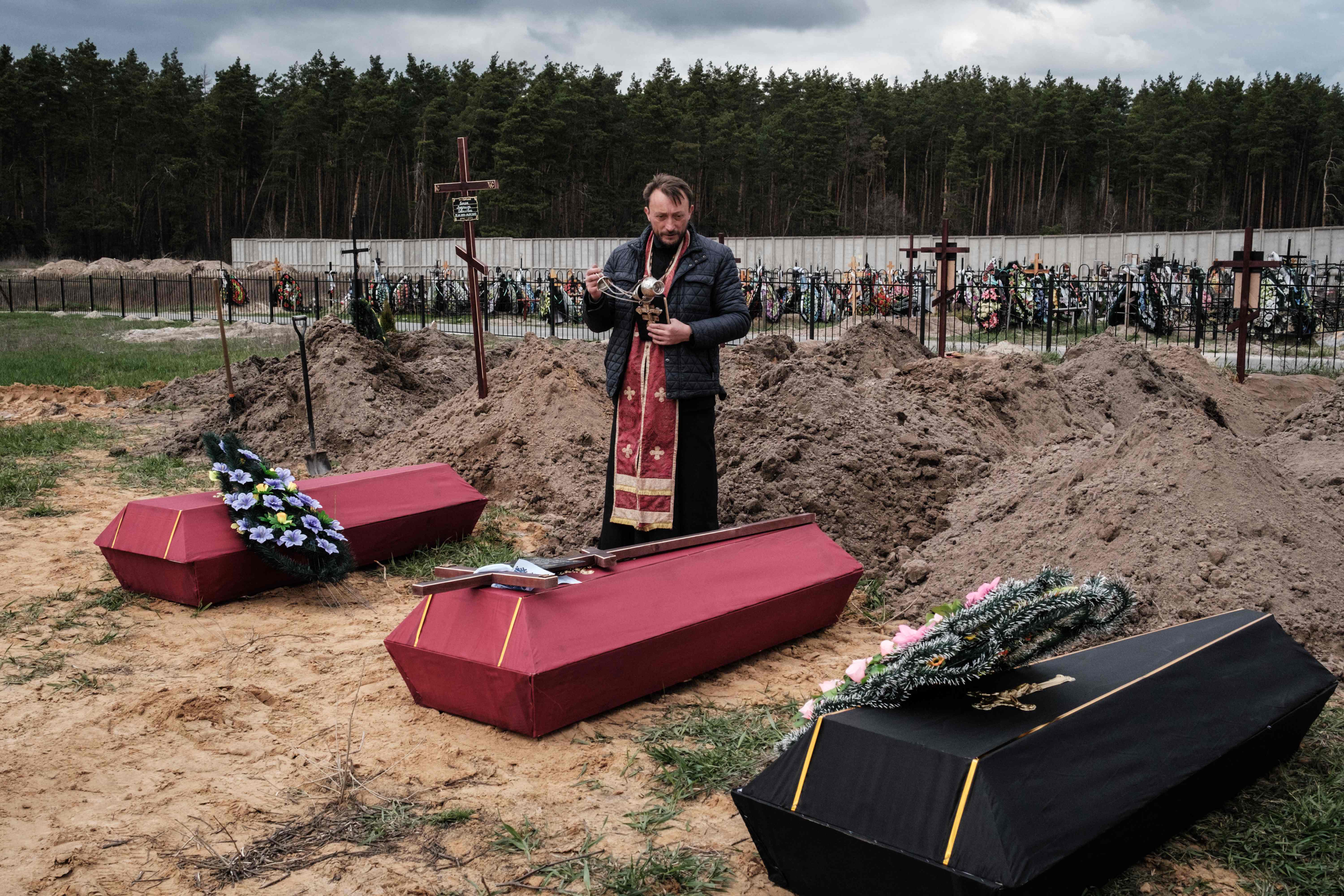 Andrii Holovine, priest of the church of St. Andrew Pervozvannoho All Saints, leads the funeral of three killed victims, at a cemetery in Bucha