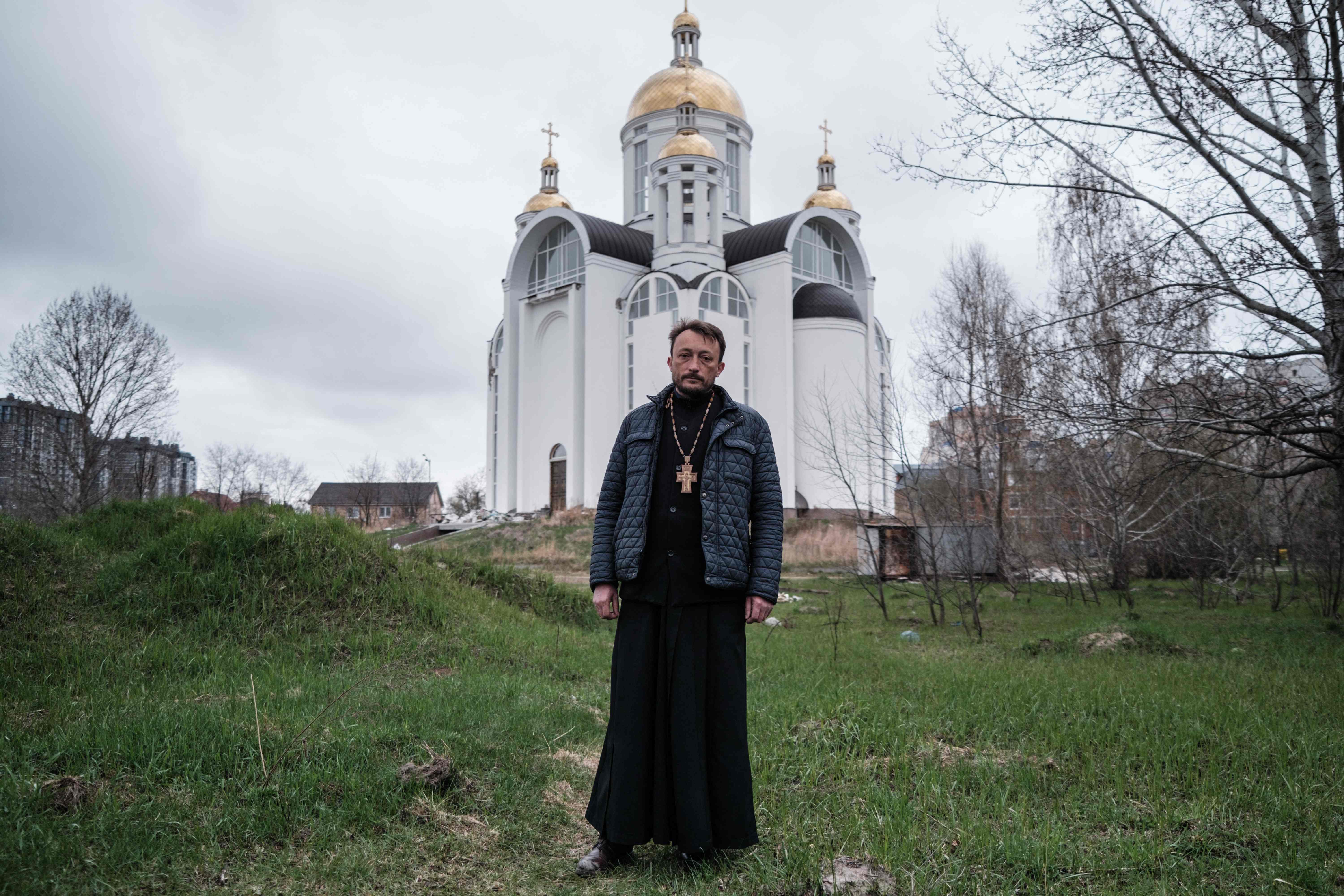 Andrii Holovine, priest of the Church of St. Andrew Pervozvannoho All Saints, poses near the church where a mass grave was found in Bucha