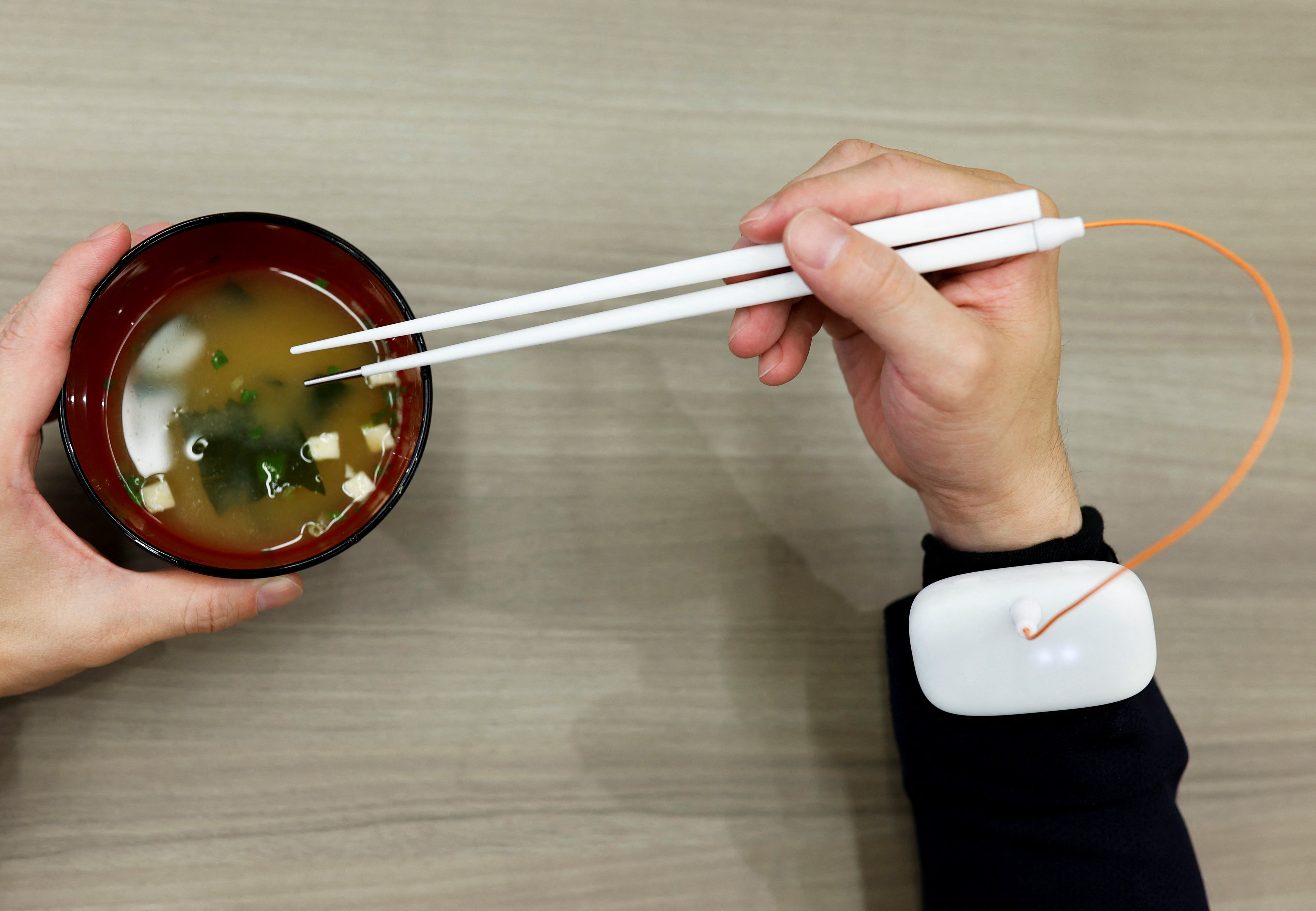 An employee of Kirin Holdings demonstrates chopsticks that can enhance food taste using an electrical stimulation waveform