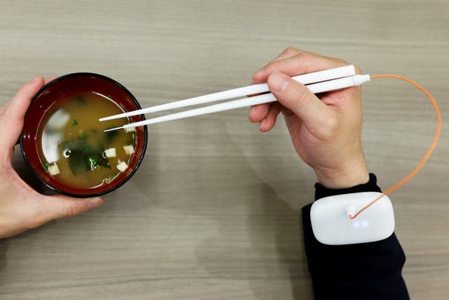 <p>An employee of Kirin Holdings demonstrates chopsticks that can enhance food taste using an electrical stimulation waveform</p>