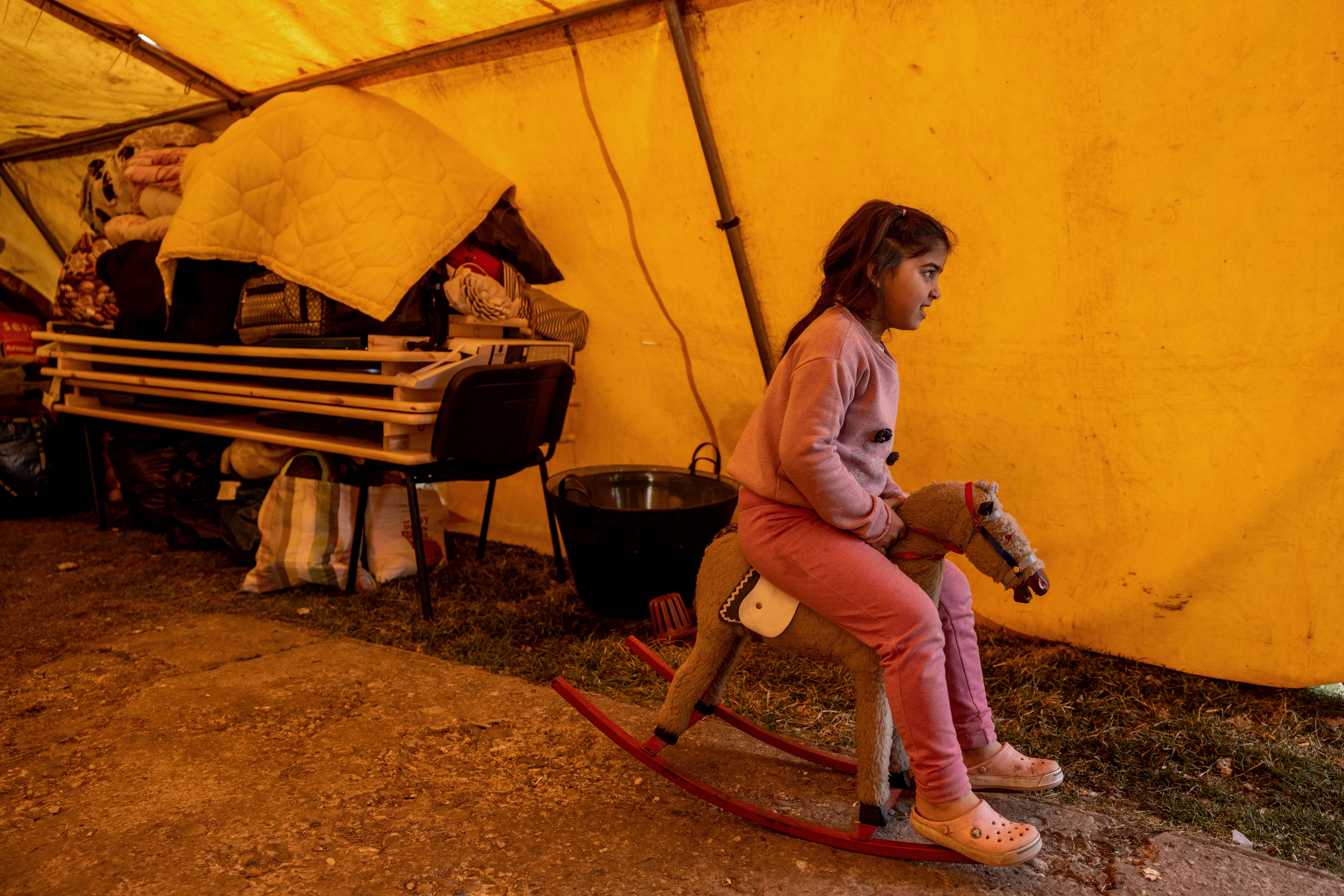 A refugee girl sit on a swing horse in a temporary shelter offered by the Free Christian Church in Uszka, Hungary