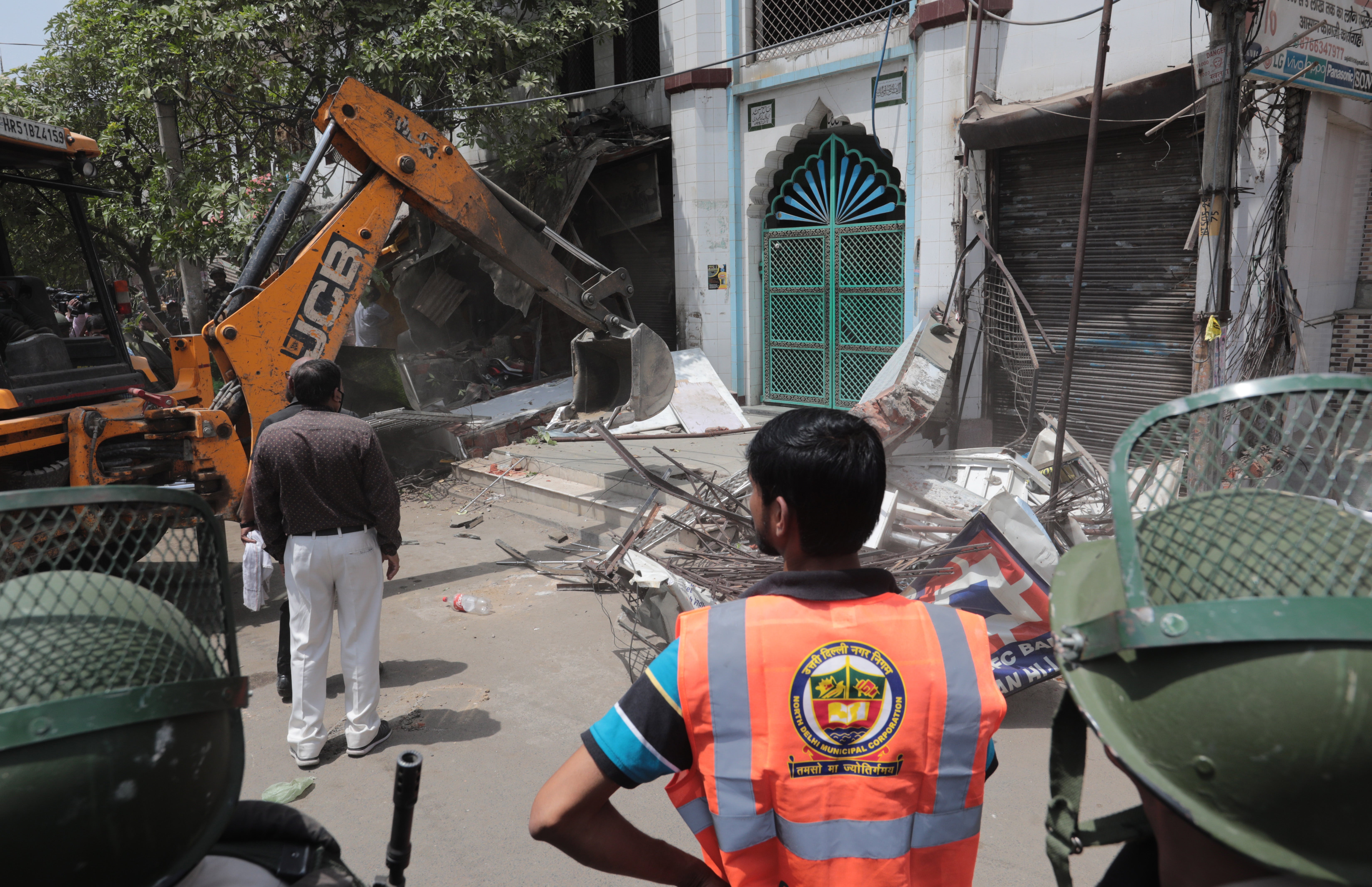A bulldozer dismantles structures outside a mosque during the demolition drive of illegal structures in Delhi's violence-hit Jahangirpuri