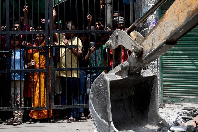 <p>Residents watch as a bulldozer demolishes an illegal structure in a residential area of Jahangirpuri in New Delhi on 21 April </p>