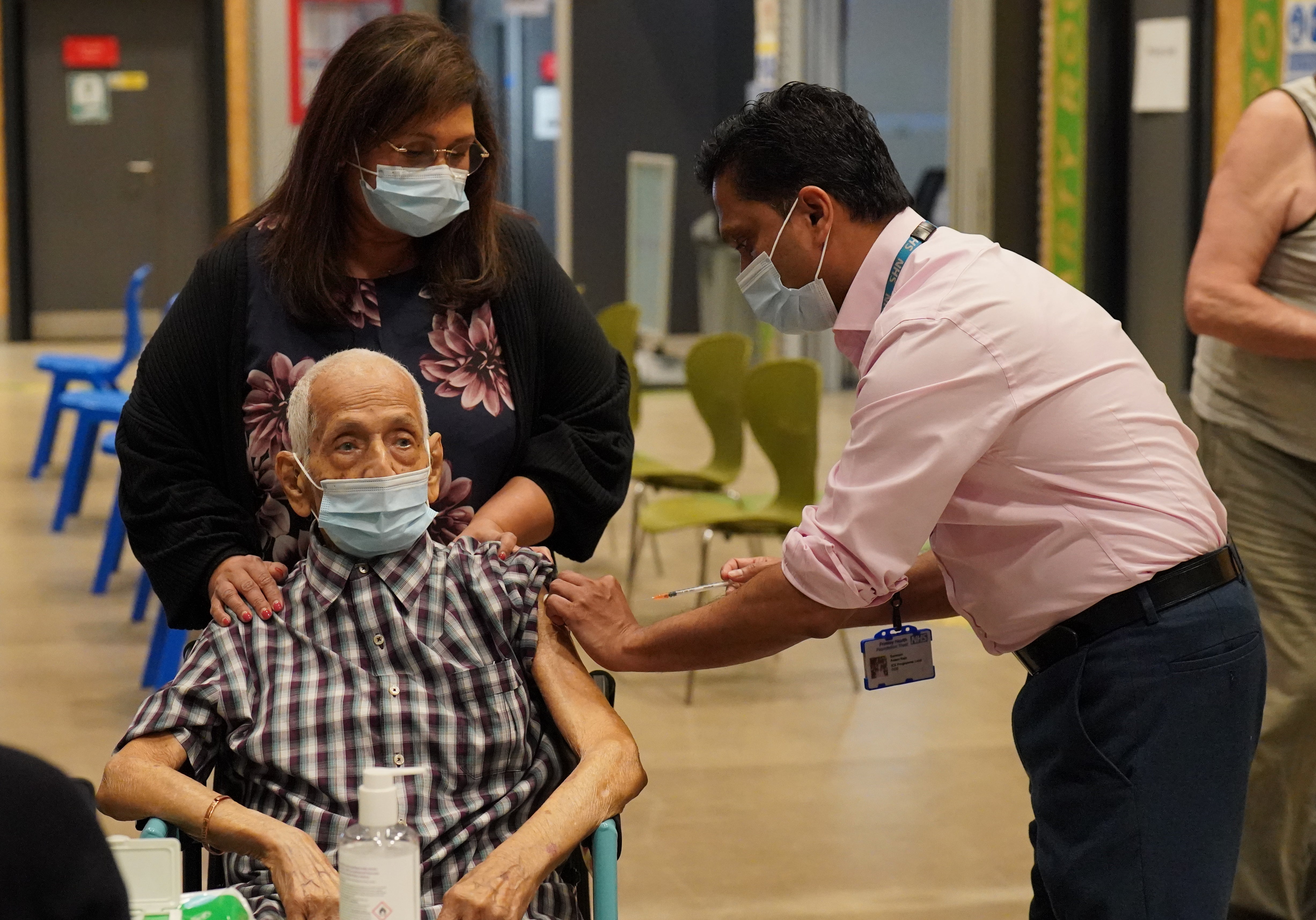 95-year-old Devraj Jhalam, accompanied by his daughter Dr Lalitha Iyer, receives a ‘spring booster’ of Covid-19 vaccine from Dr Nithya Nanda at the Salt Hill Activity Centre vaccination clinic in Slough, Berkshire (Jonathan Brady/PA)