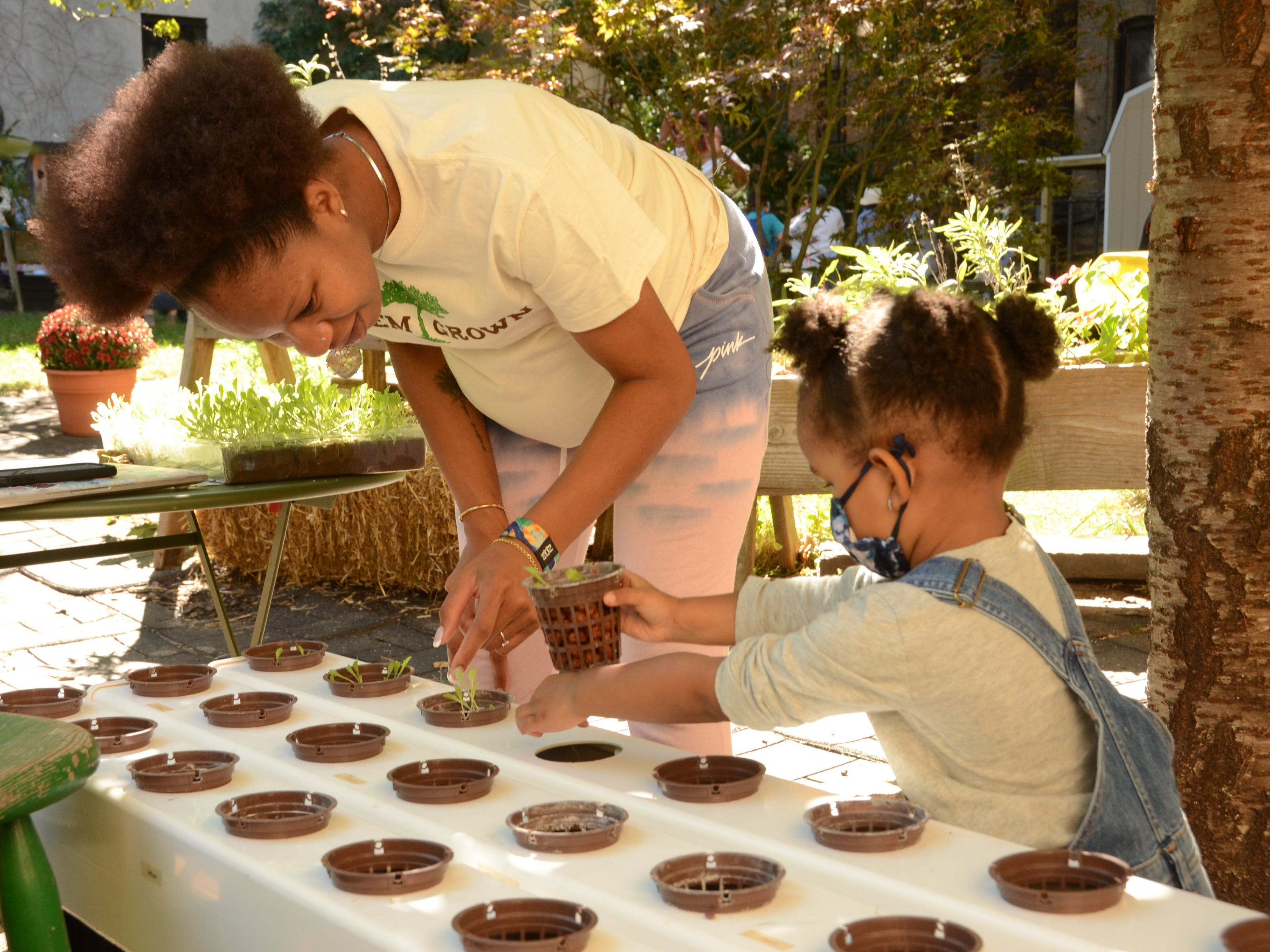 A Harlem Grown staff member works with a student at the community garden
