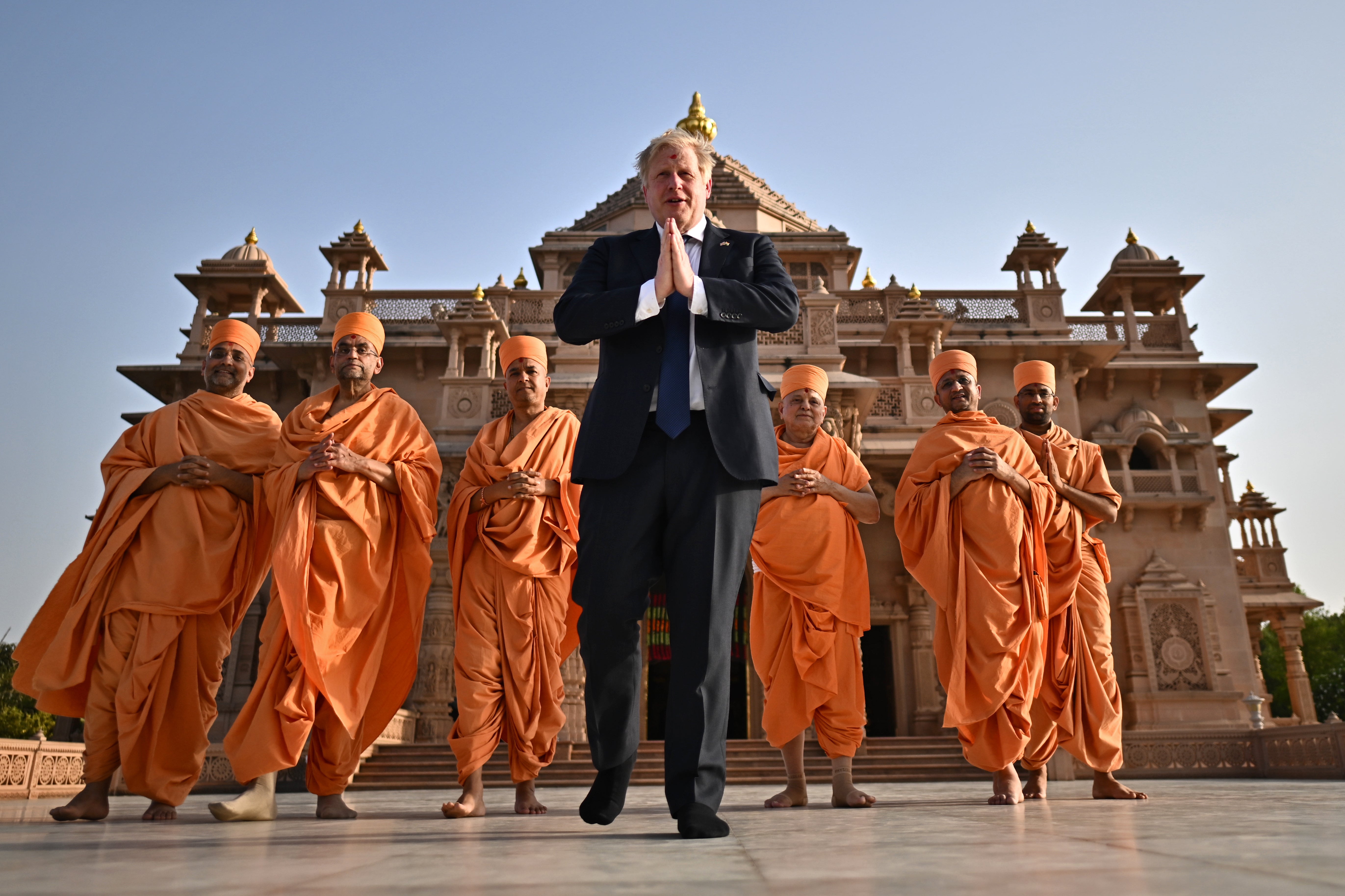 Prime Minister Boris Johnson (C) poses with sadhus or Hindu holymen in front of the Swaminarayan Akshardham temple during his two day trip to India on April 21, 2022 in Gandhinagar, India. During his two-day visit to India Boris Johnson is expecting to seal new collaborations on defence and green energy as he seeks to reduce the country’s dependence on Russian fossil fuels and military equipment