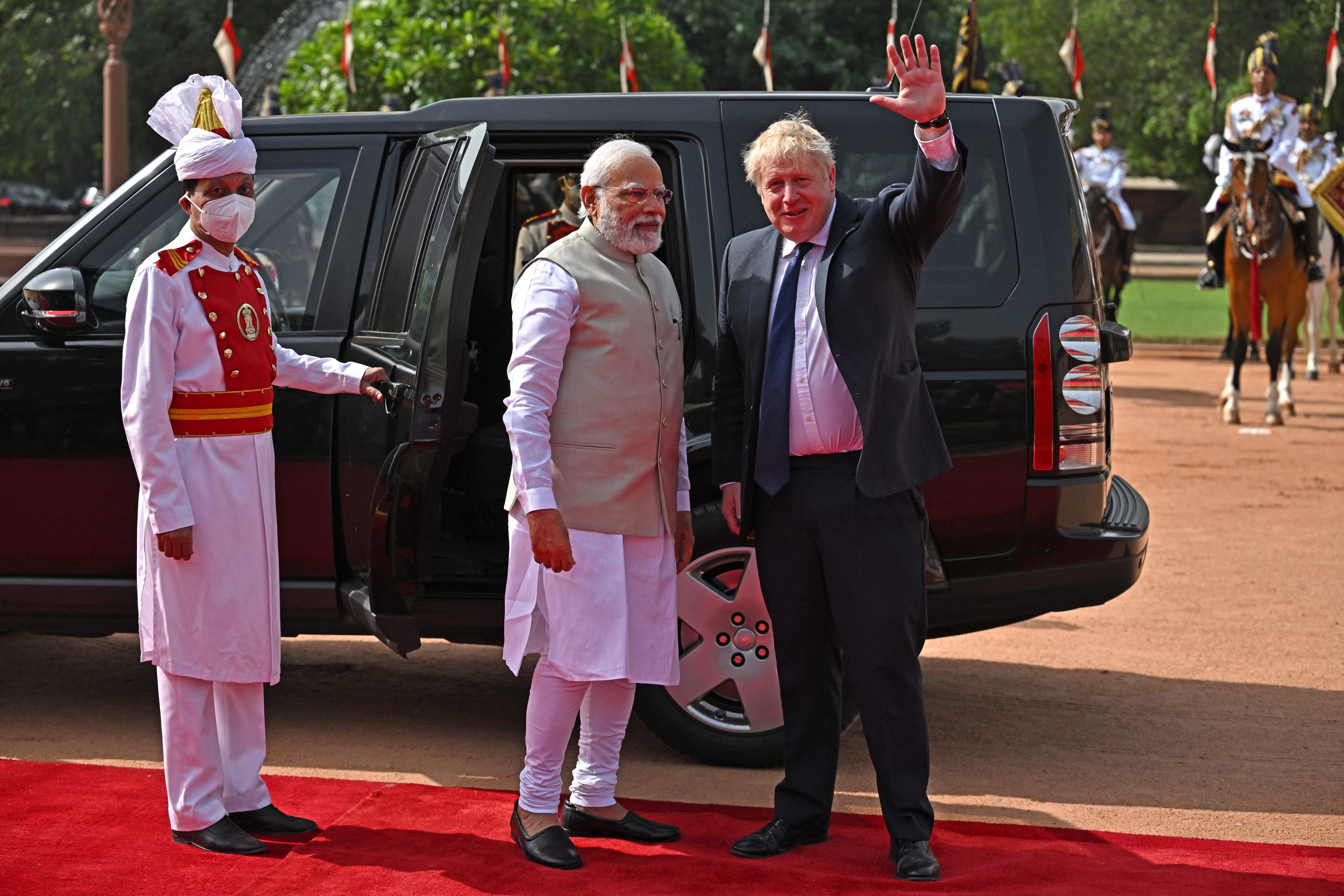 Britain’s Prime Minister Boris Johnson (R) waves as his Indian counterpart Narendra Modi watches after Johnson’s ceremonial reception at India’s presidential palace Rashtrapati Bhavan in New Delhi on April 22, 2022