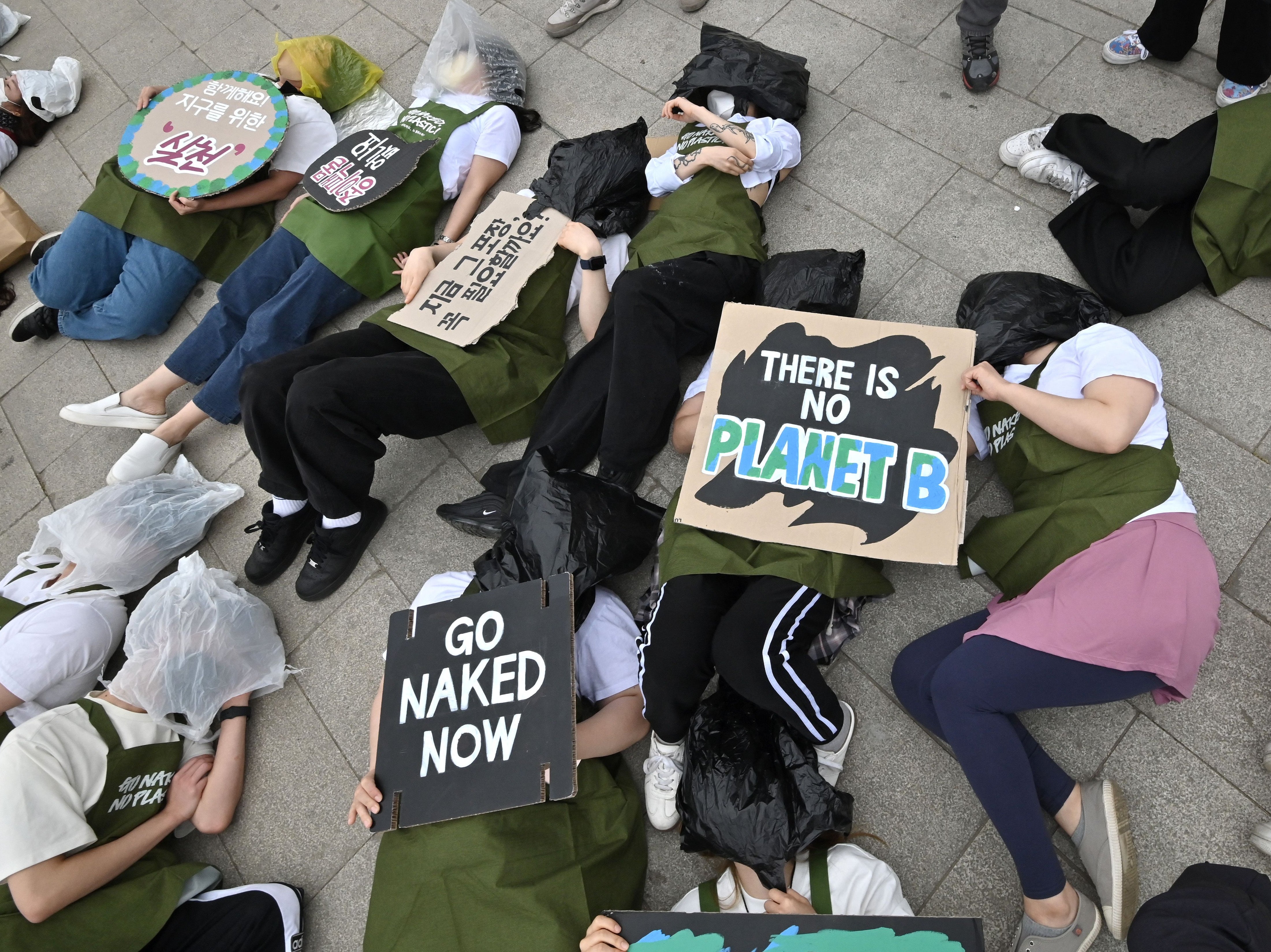 South Korean environmental activists lie on the ground with plastic waste during a campaign marking Earth Day against climate change