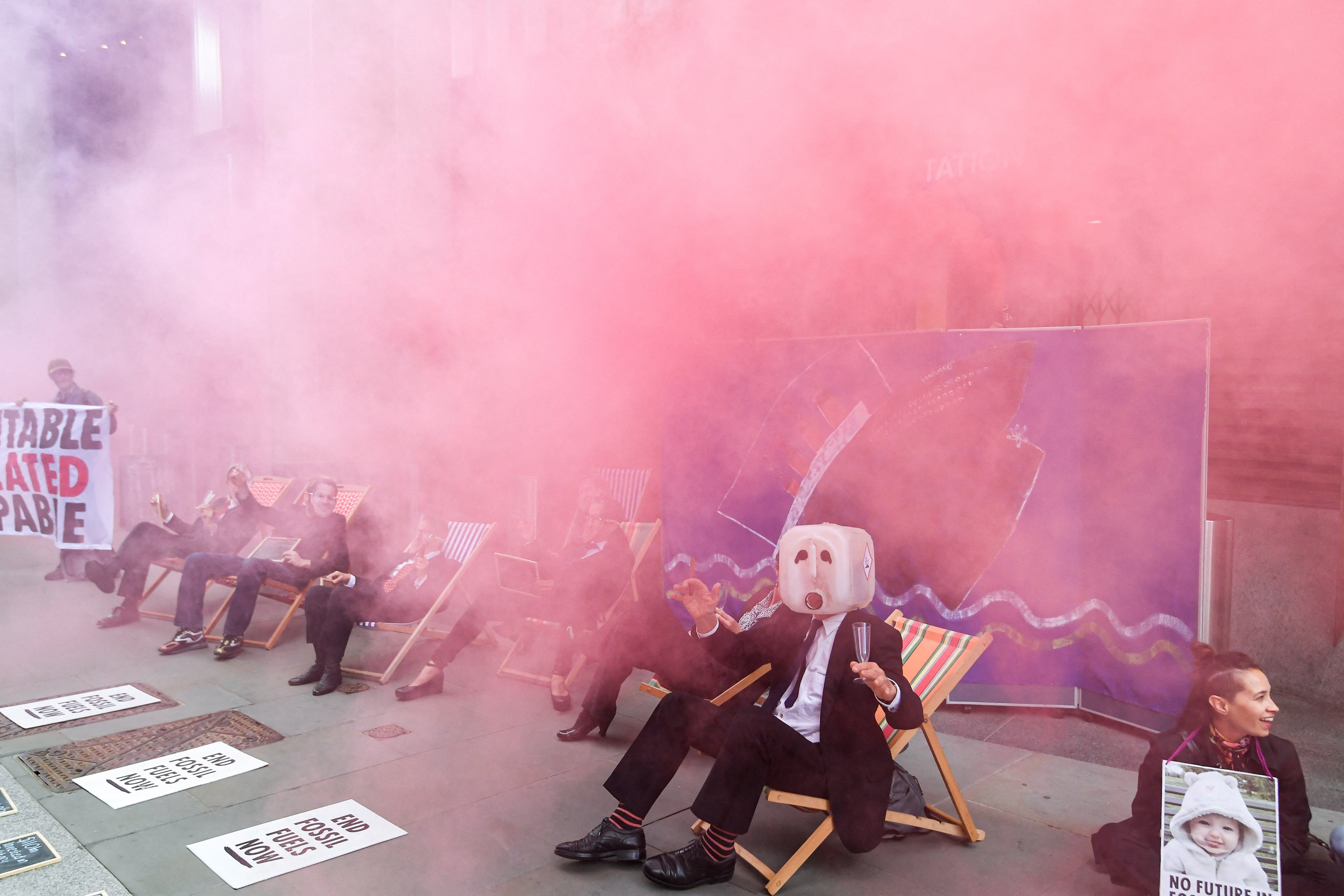 Pink smoke billows over members of Extinction Rebellion staging a protest against the use of and investment in fossil fuel, outside offices of Vanguard Asset Management on Earth Day