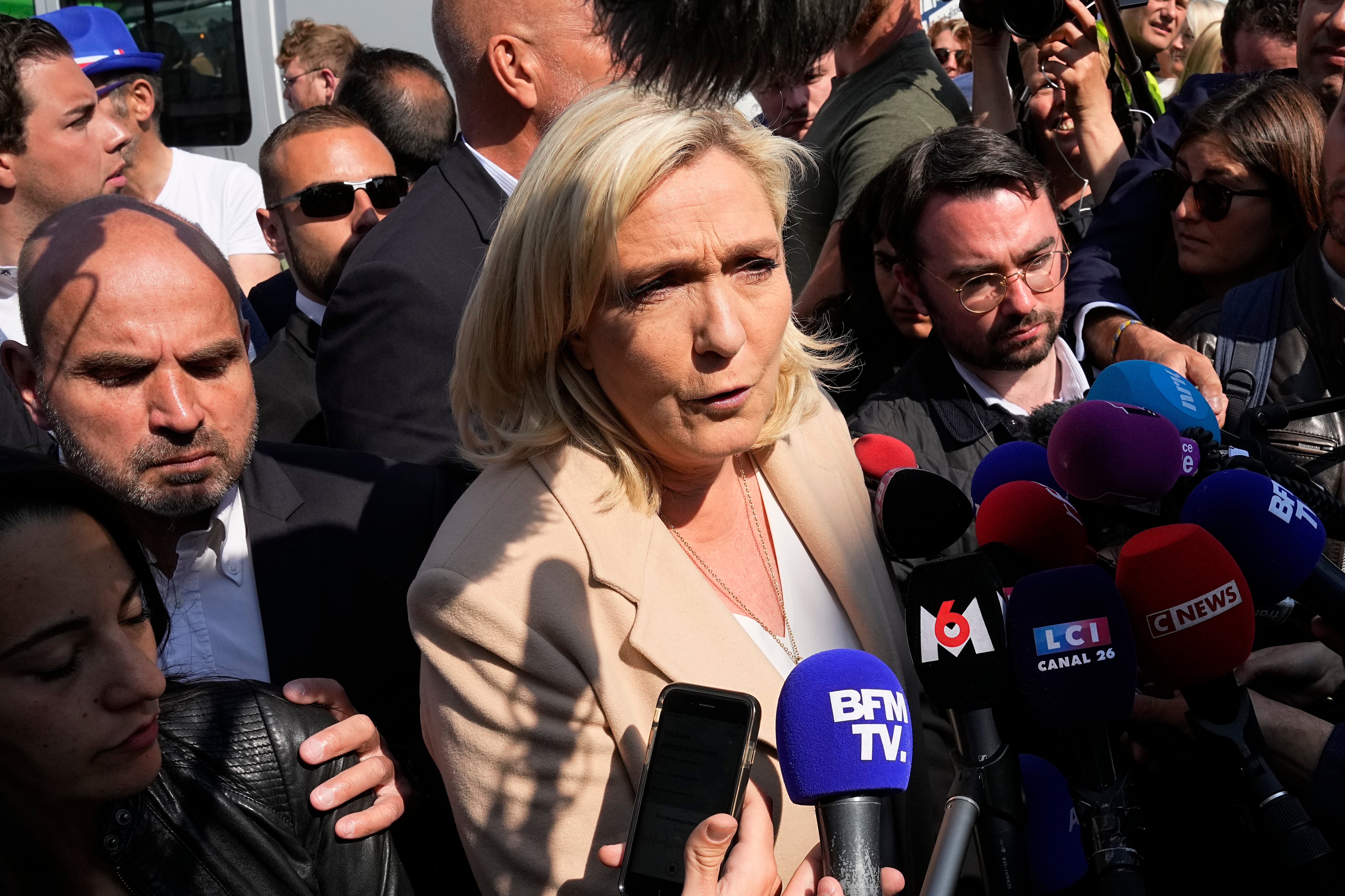 Marine Le Pen answers reporters as she campaigns at a street market in Etaples, northern France.