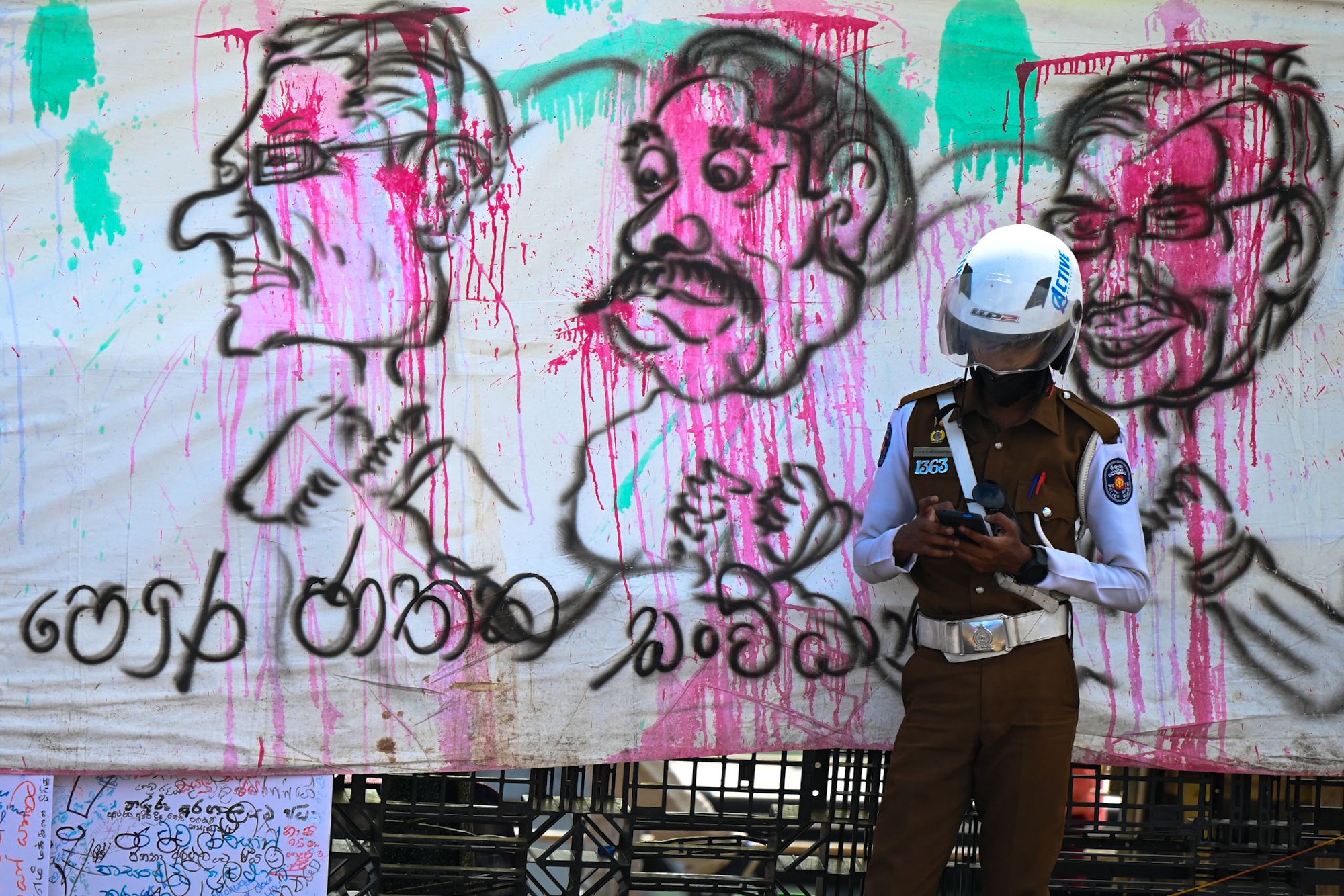 A policeman stands guard in front of a banner during an ongoing anti-government demonstrations near the president’s office in Colombo