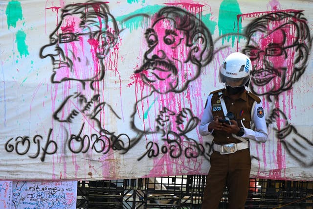 <p>A policeman stands guard in front of a banner during an ongoing anti-government demonstrations near the president’s office in Colombo</p>