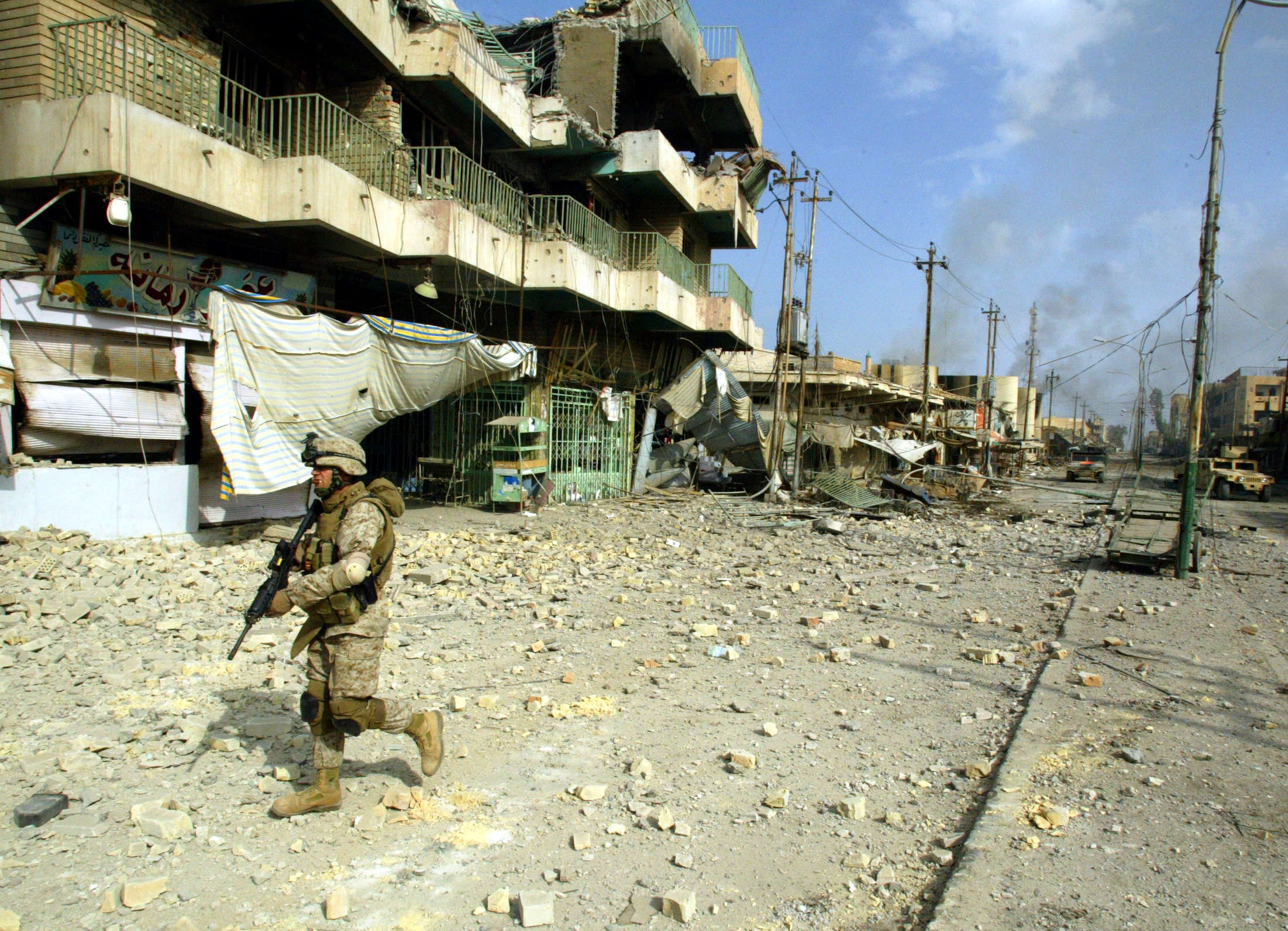 A US marine from the 3/5 Lima company walks towards a destroyed building along the main street in the restive city of Fallujah in 2004