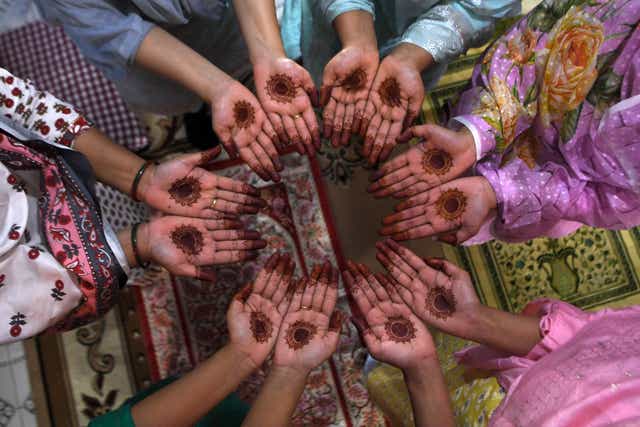 <p>Women of the same family pose for pictures with hennas decoration on their hand after offering a special prayer in their home during Eid-al-Fitr 2021 </p>