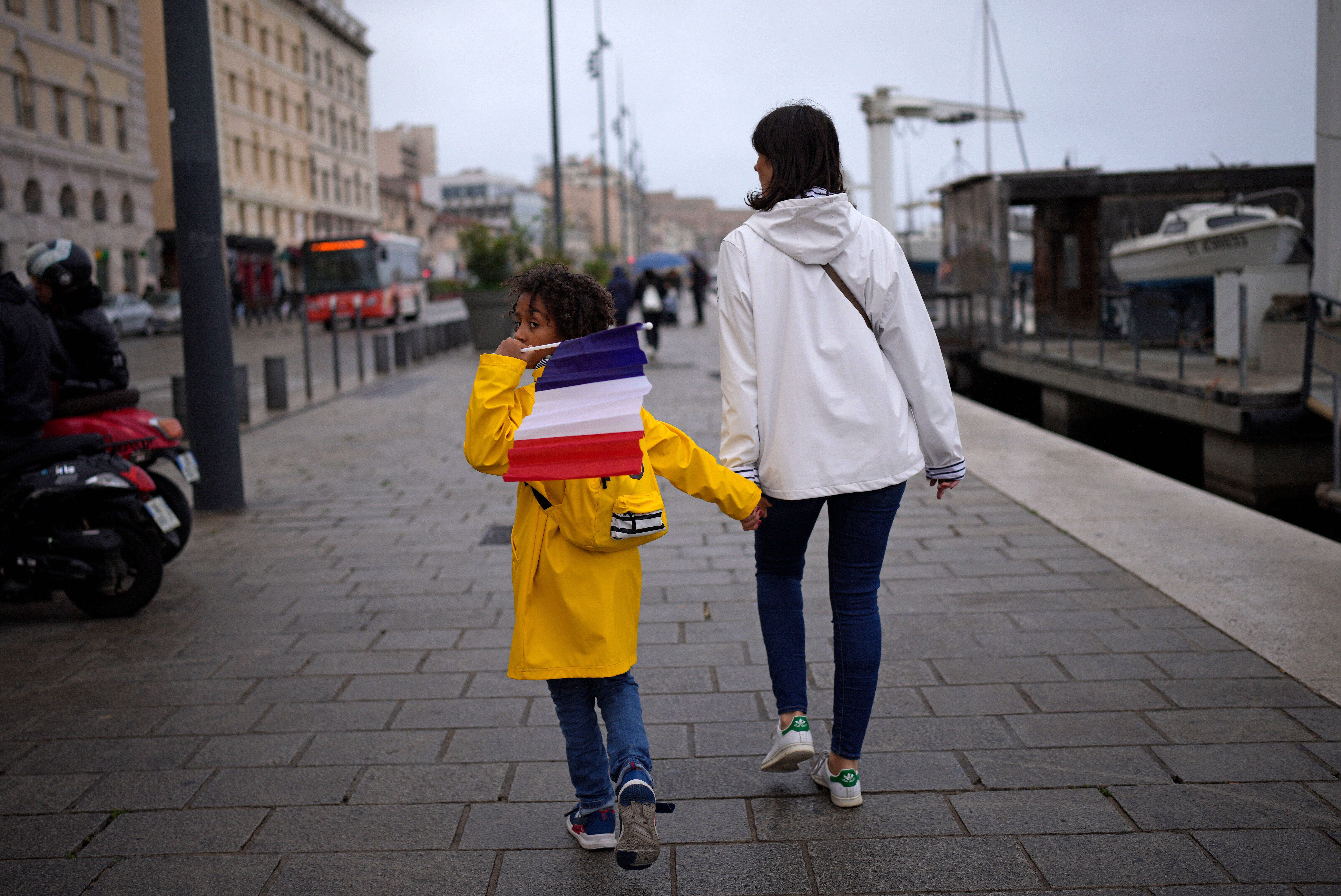 A child hold a French flag as they walk in Marseille, southern France