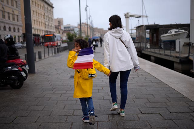 <p>A child hold a French flag as they walk in Marseille, southern France </p>