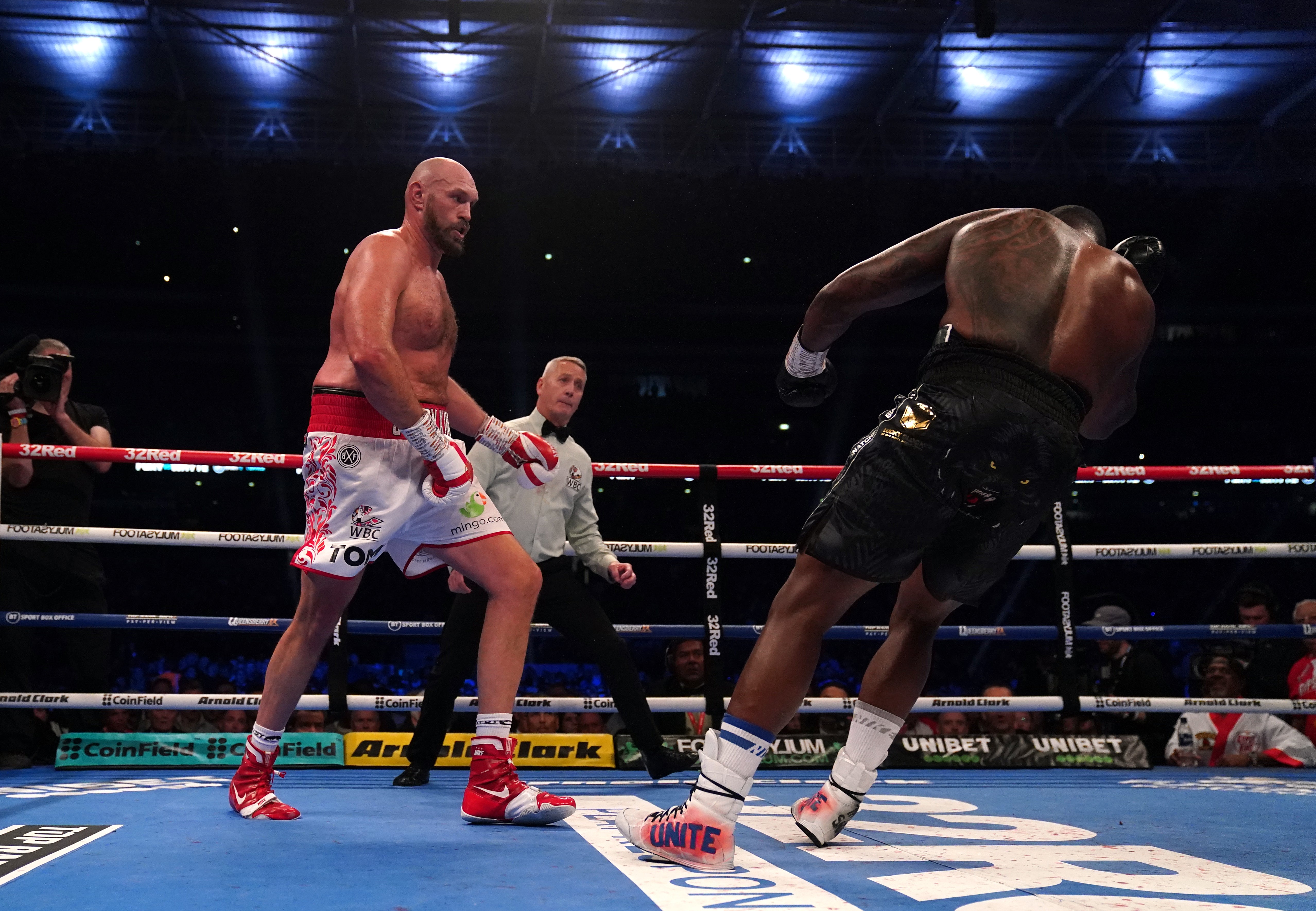 Tyson Fury (left) knocks down Dillian Whyte during the WBC heavyweight title fight at Wembley Stadium (Nick Potts/PA)