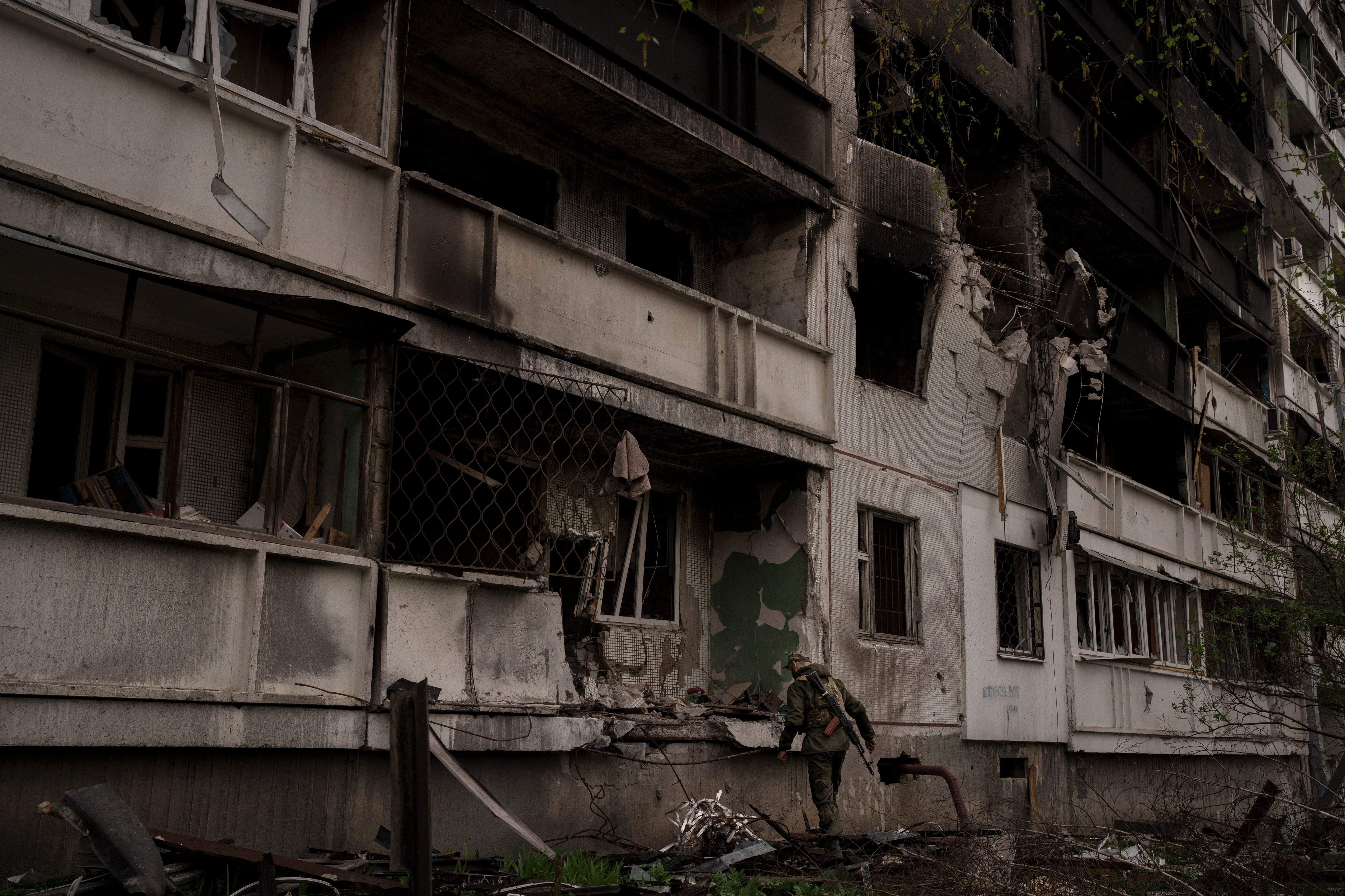 <p>A Ukrainian serviceman inspects a heavily damaged apartment building after Russian bombardment in Kharkiv</p>