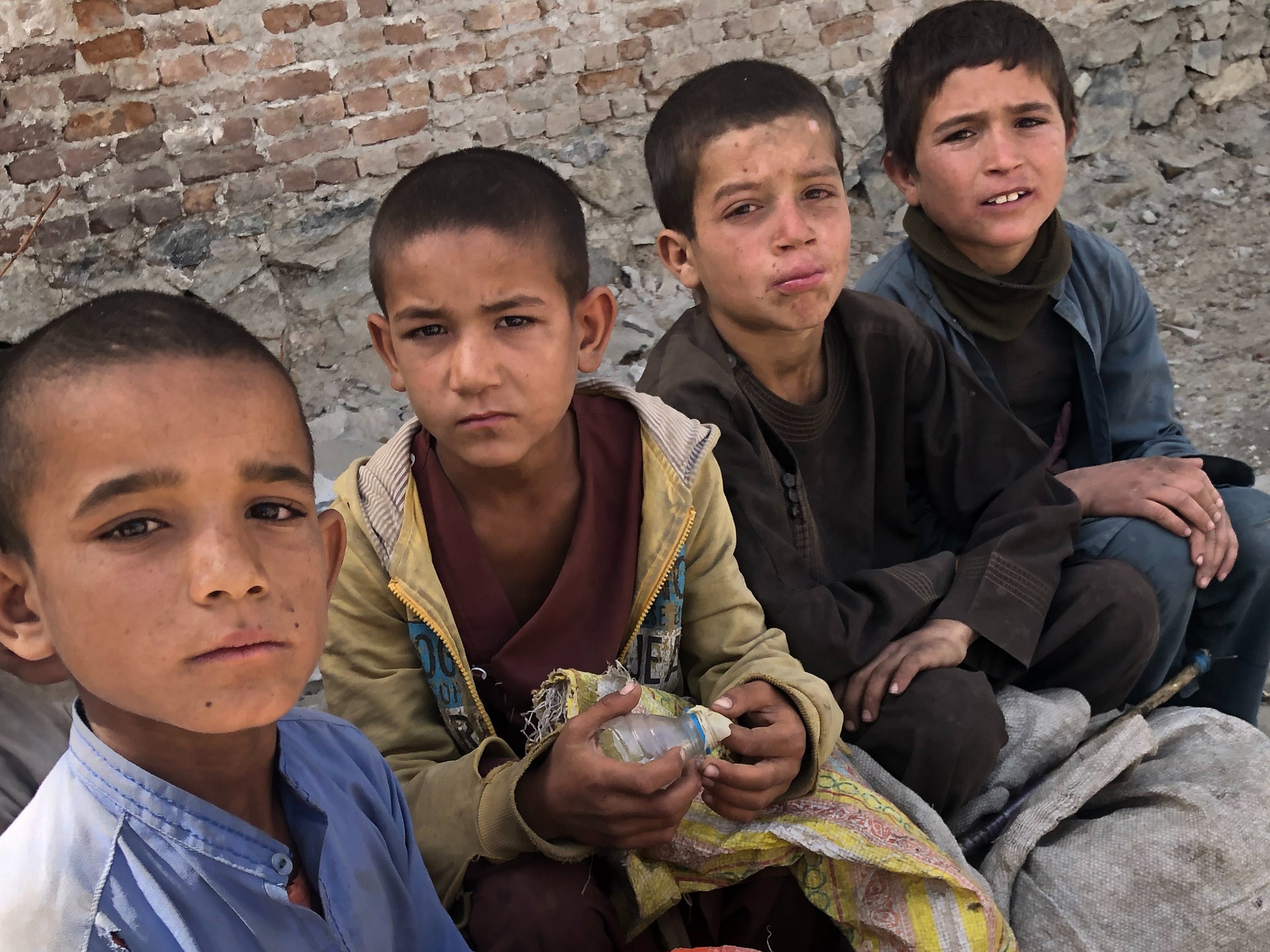 Four young boys take a break from scavenging for cans and bottles in Kabul