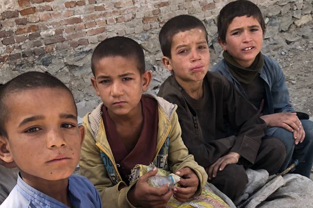 <p>Four young boys take a break from scavenging for cans and bottles in Kabul</p>
