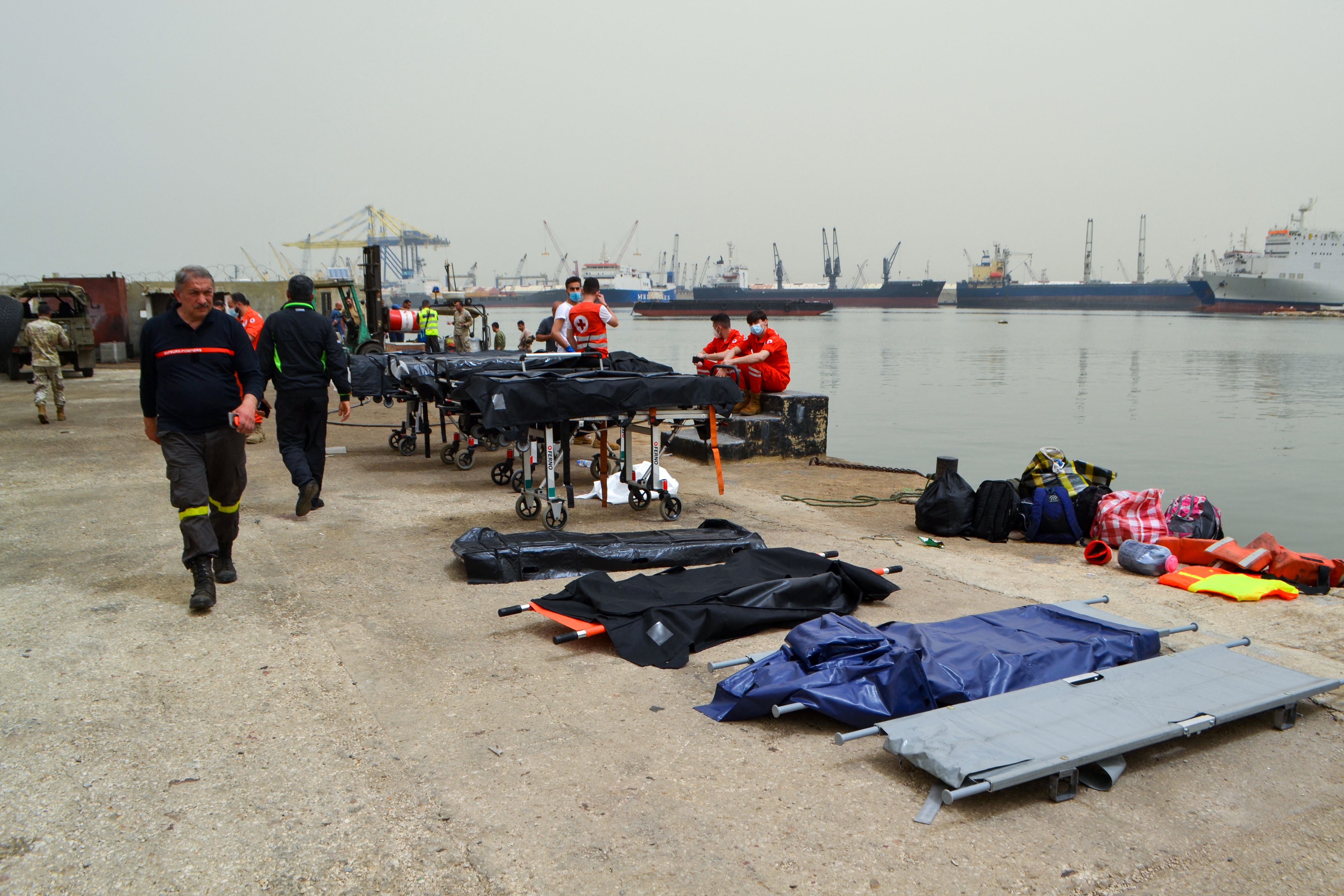 Medics wait on the pier as soldiers search for survivors off the coast of the northern Lebanese city of Tripoli, 24 April 2022