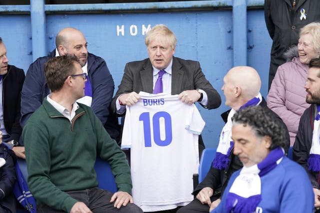 Boris Johnson holds a no 10 shirt with his name as he sits with fans during a visit to Bury FC (Danny Lawson/PA)