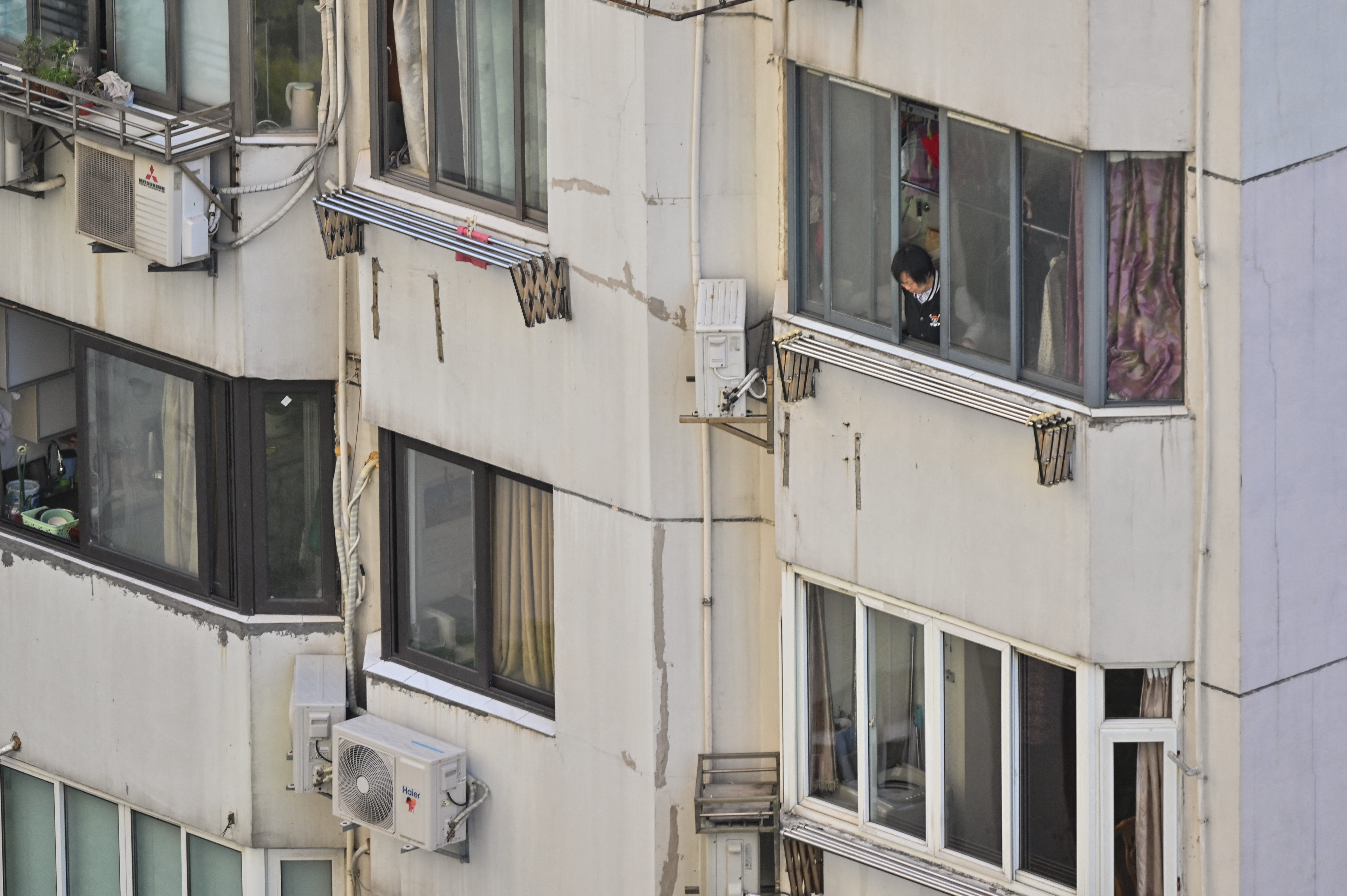 A woman looks out of an apartment during lockdown in the Jing’an district in Shanghai on April 9, 2022