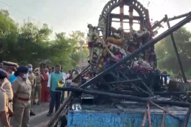 <p>People gather around a chariot that was damaged after a high voltage power wire fell on it, killing at least 11 people, during a procession in a temple festival in Kalimedu village</p>