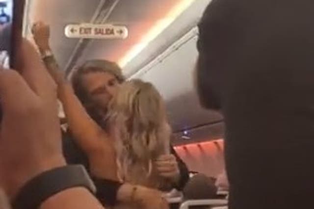 <p>The happy couple kisses under the Exit sign as fellow passengers cheer</p>