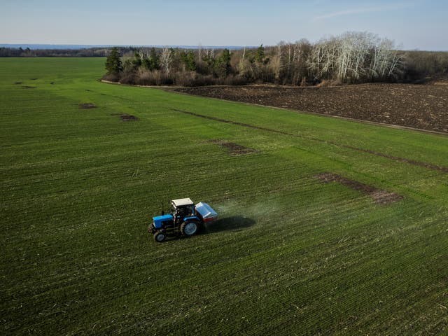 <p>An aerial view shows a tractor spreading fertiliser on a wheat field near the village of Yakovlivka after it was hit by an aerial bombardment outside Kharkiv on 5 April</p>