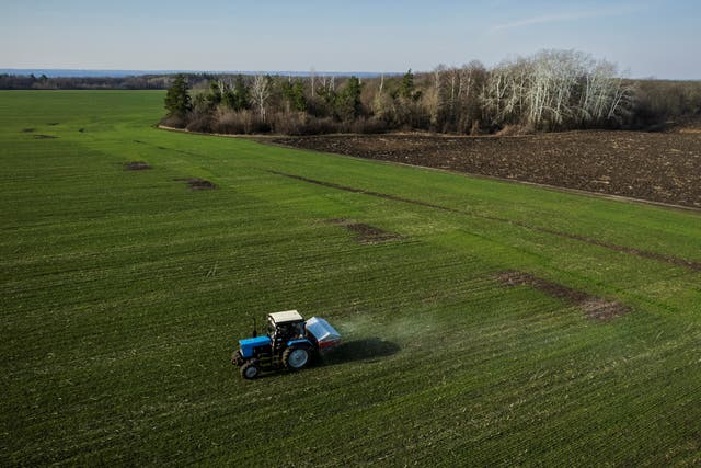 <p>An aerial view shows a tractor spreading fertiliser on a wheat field near the village of Yakovlivka after it was hit by an aerial bombardment outside Kharkiv on 5 April</p>