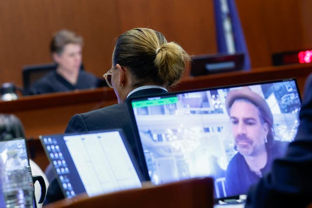 El actor Johnny Depp comparece ante el tribunal mientras se reproduce un testimonio pregrabado de Christian Carino en las pantallas del Tribunal de Circuito del Condado de Fairfax en Fairfax, Virginia, el miércoles 27 de abril de 2022.