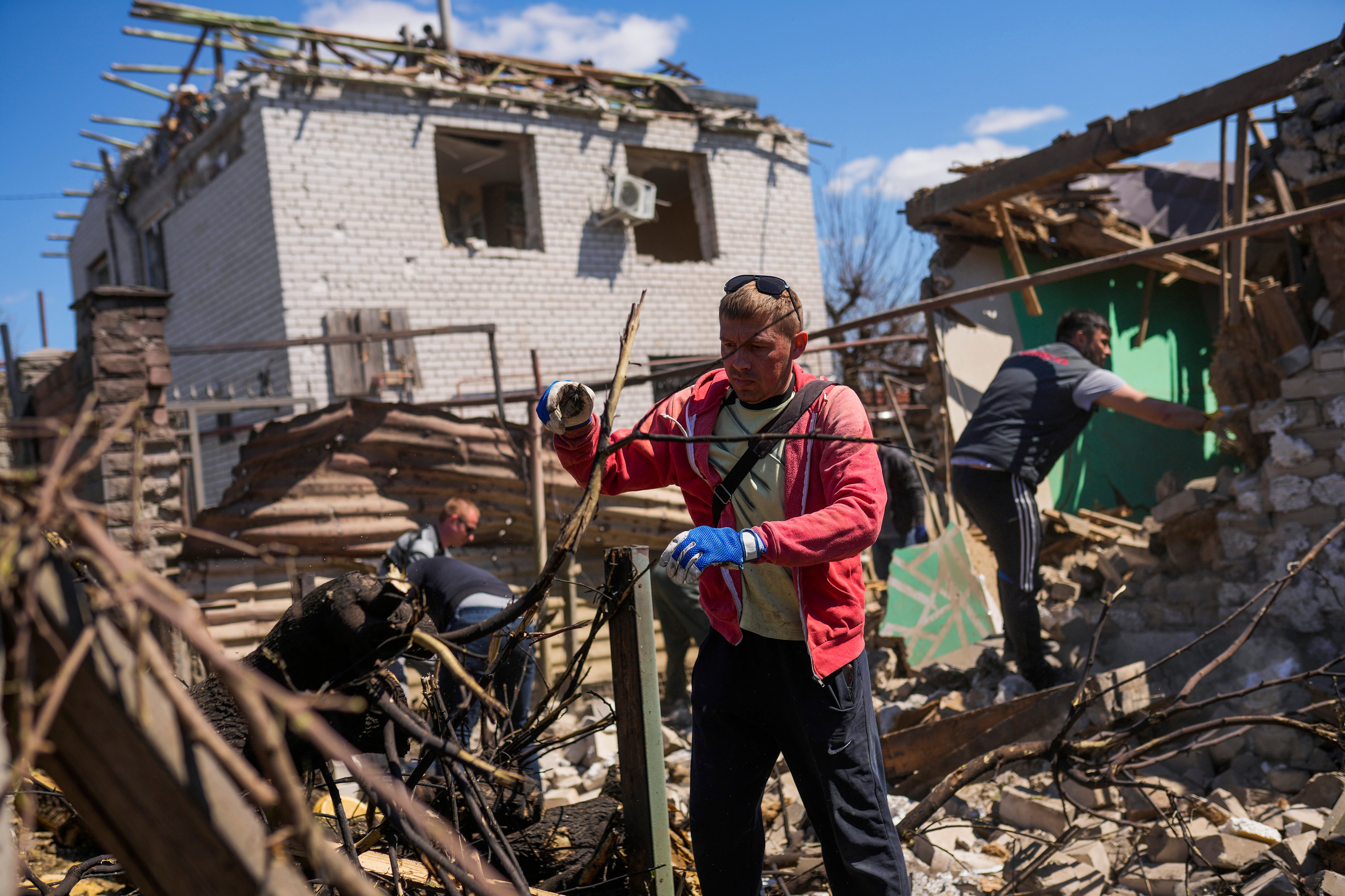 Locals remove debris from destroyed houses after a Russian rocket hit a residential area in Zaporizhzhia, Ukraine (Francisco Seco/AP)