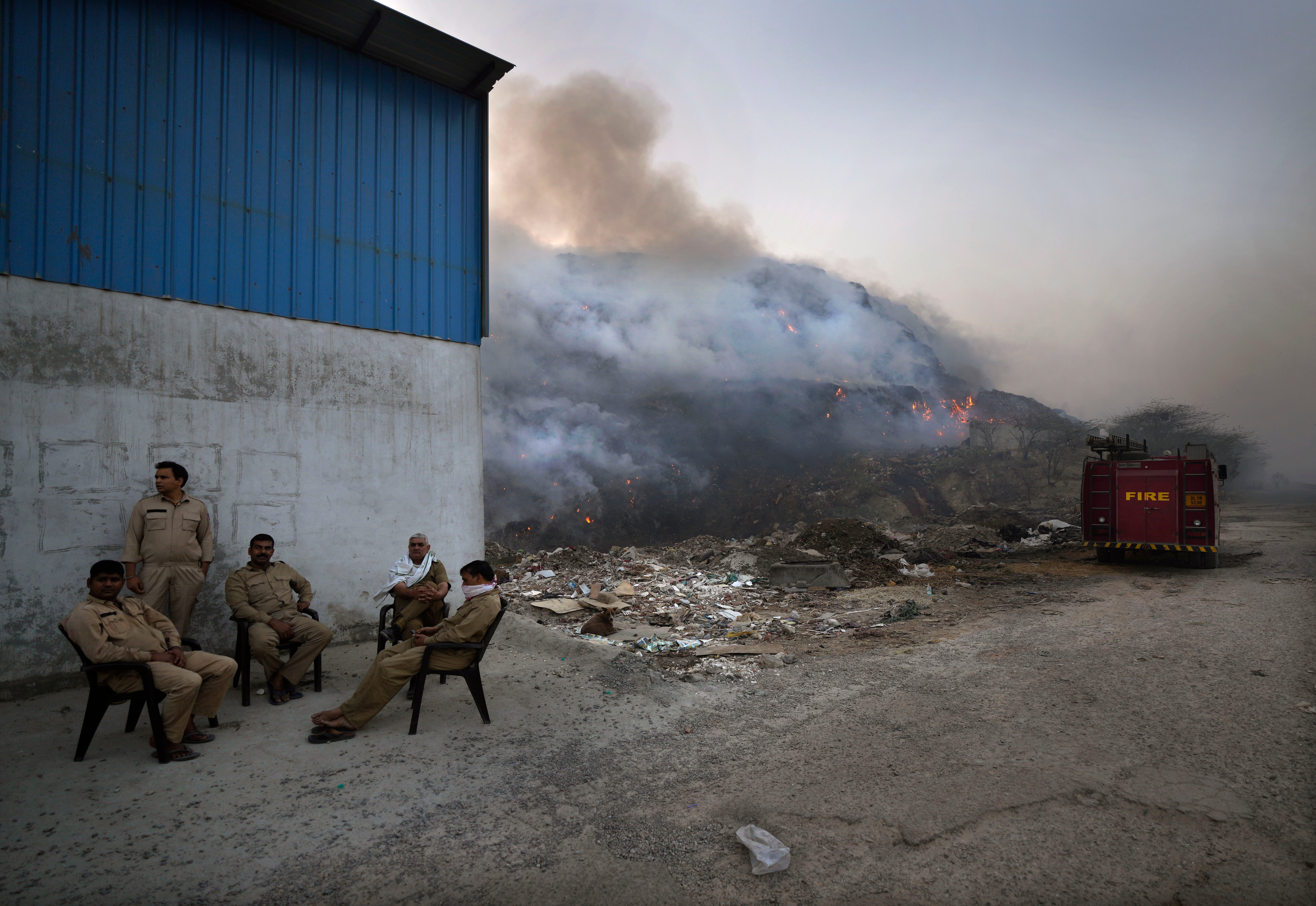 Delhi fire officials take a break while dousing a fire at the Bhalswa landfill in New Delhi on Wednesday.