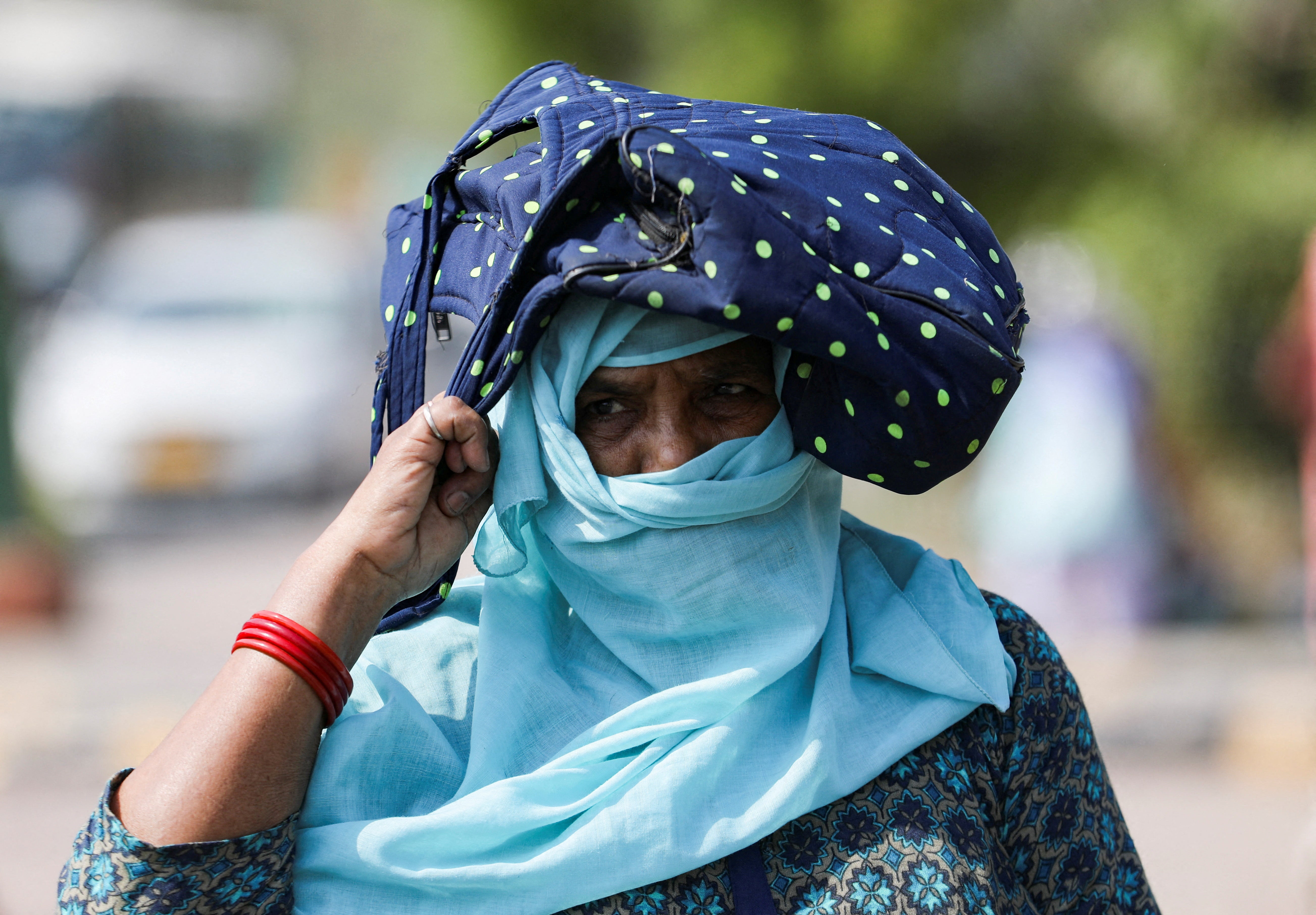 A woman uses her bag to protect herself from the sun in New Delhi