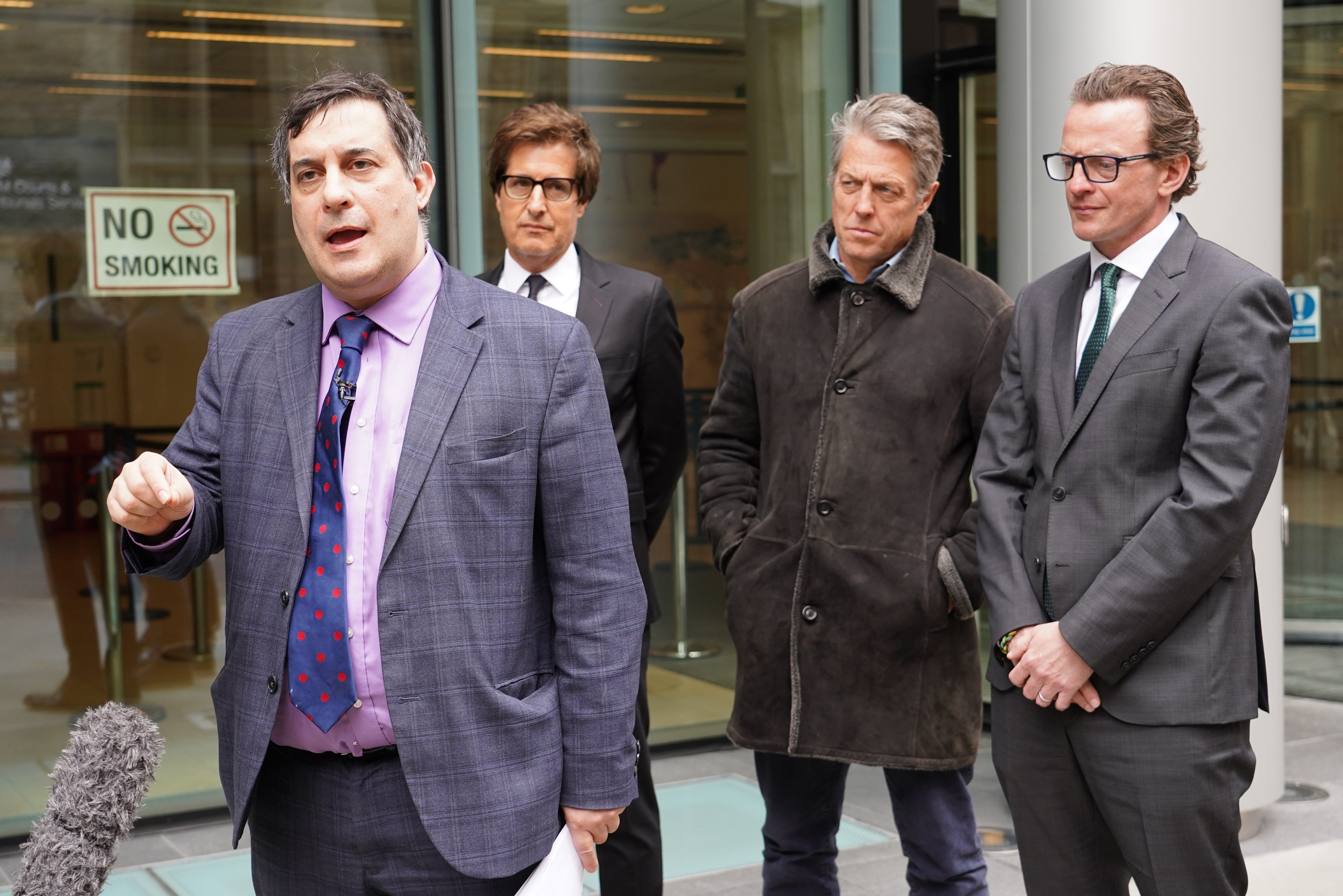 Actor Hugh Grant looks on as campaigner Dr Evan Harris speaks to the media after settling a legal action against News Group Newspapers over phone hacking claims (Ian West/PA)