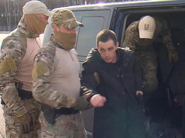 <p>Trevor Reed, 30, being escorted by Russian service members </p>