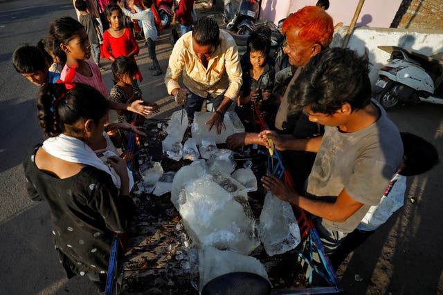 <p>A man breaks a block of ice to distribute it among the residents of a slum during hot weather in Ahmedabad</p>