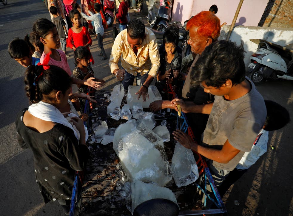 <p>A man breaks a block of ice to distribute it among the residents of a slum during hot weather in Ahmedabad</p>