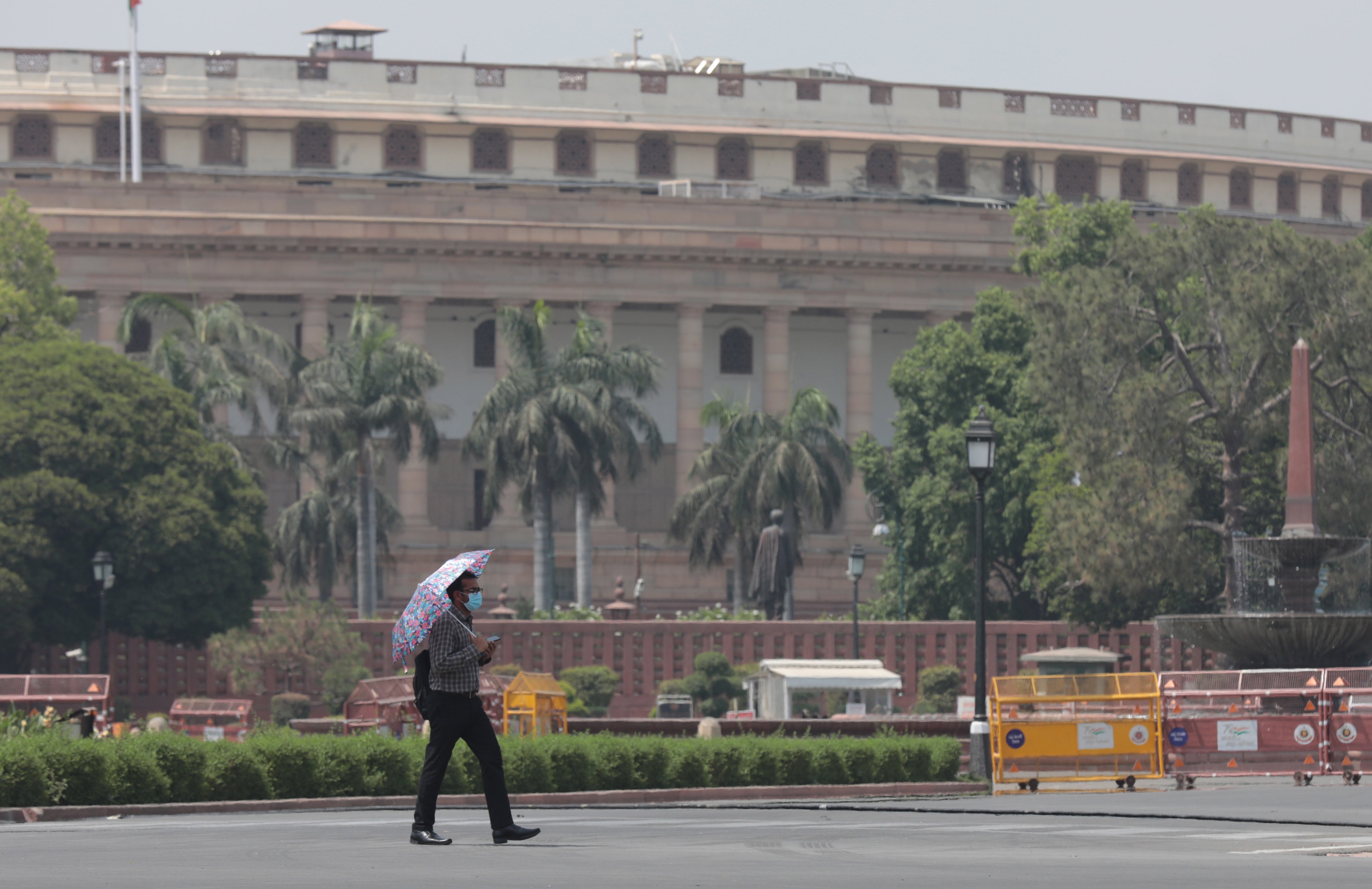 An Indian man carries an umbrella to avoid heat waves as the temperature rises in New Delhi, 28 April 2022