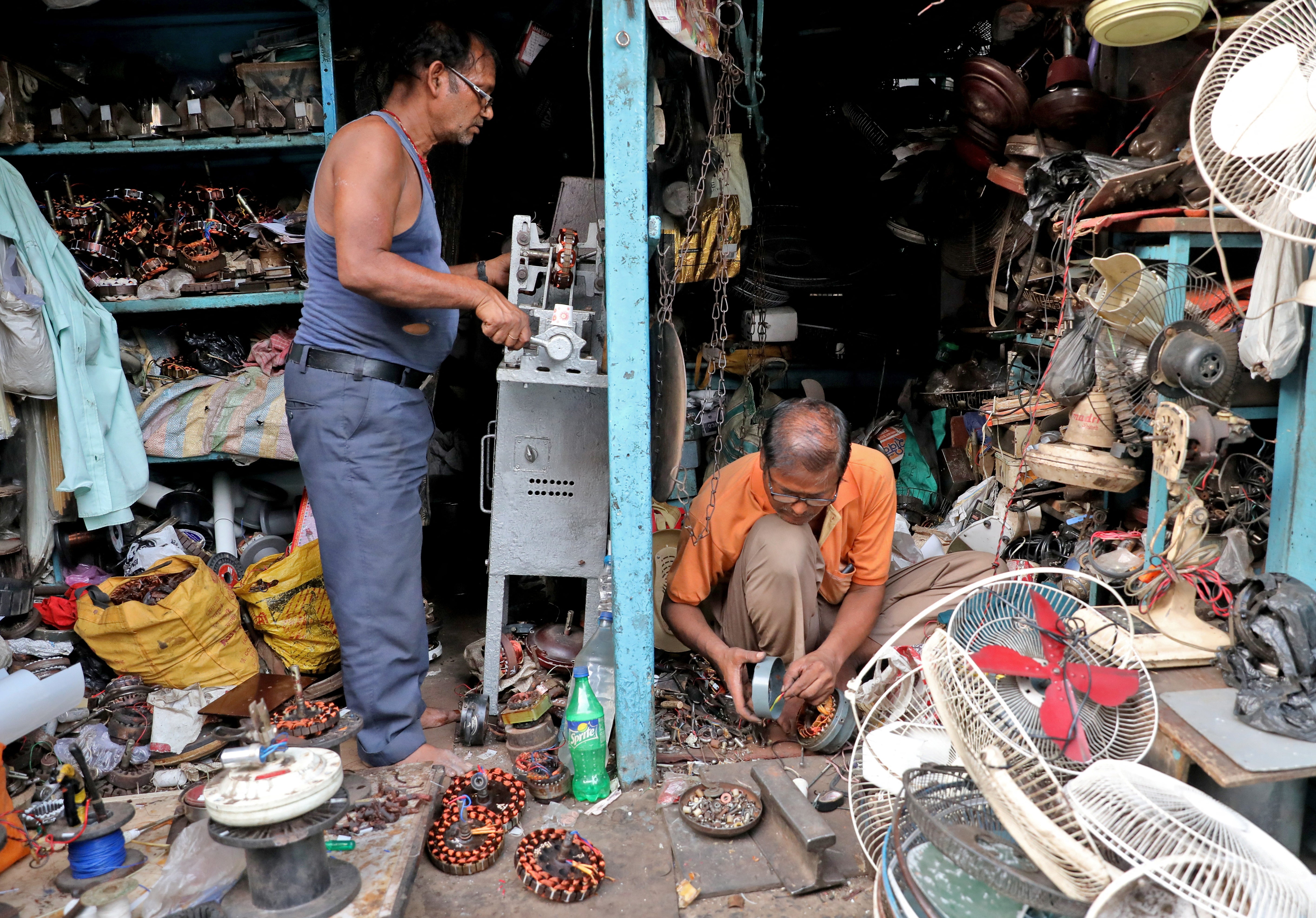 Men repair fans inside a workshop in Kolkata, India, 28 April 2022