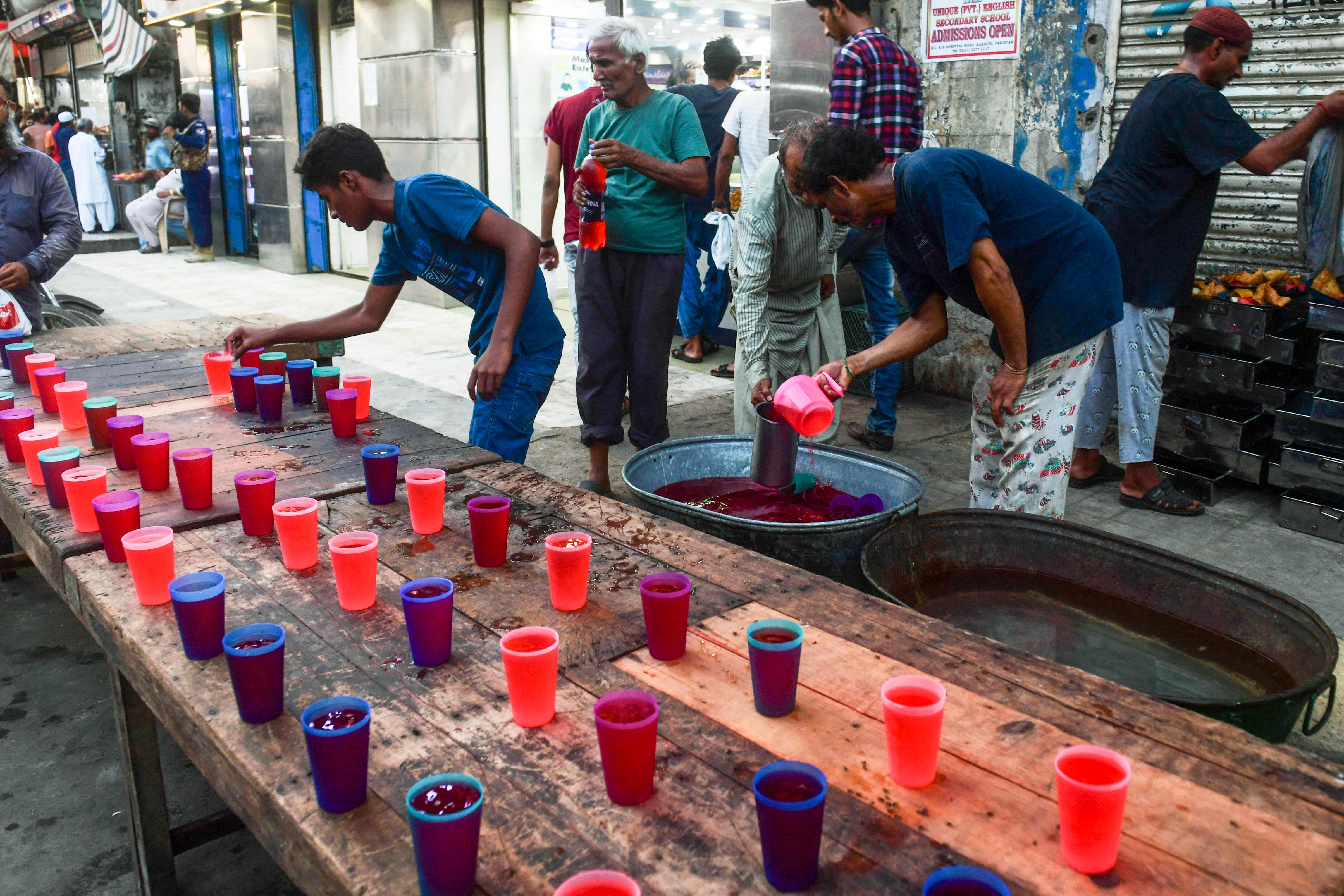 In this picture taken on April 28, 2022, volunteers prepare Rooh Afza drinks, a sweet beverage in Karachi, Pakistan as the country observes sweltering heat