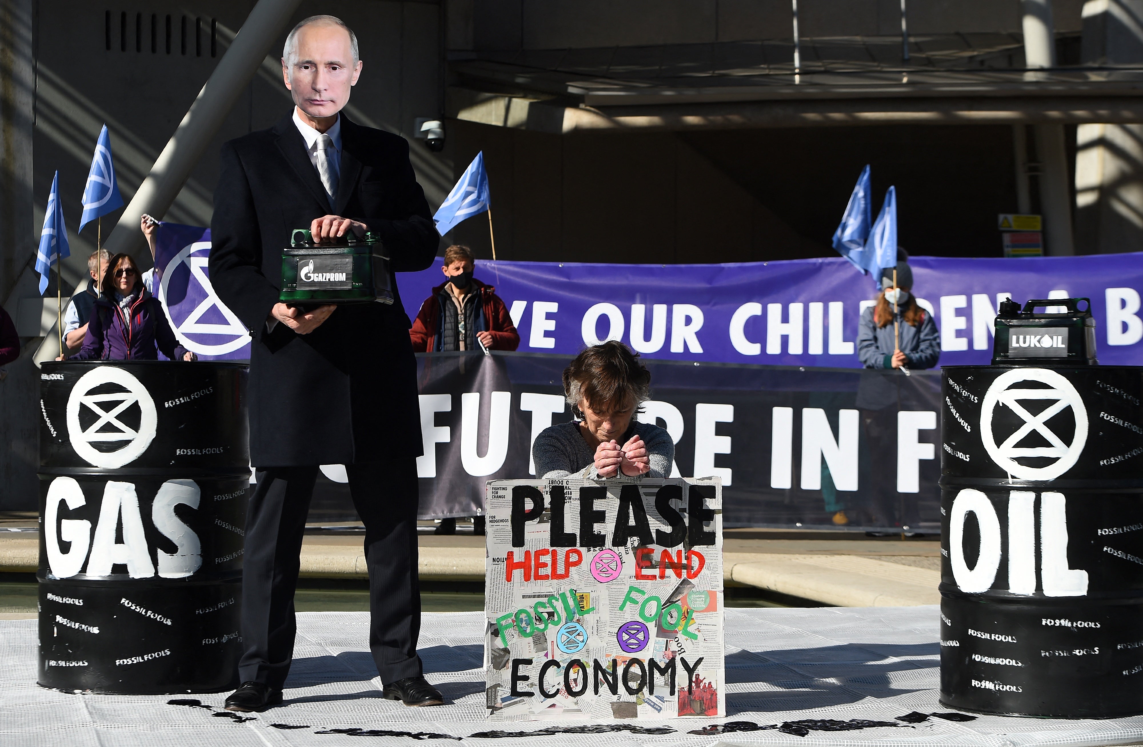 A masked activist from Extinction Rebellion holds a container decorated with the Gazprom logo at a protest in Edinburgh