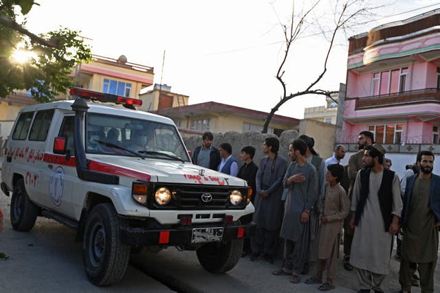 <p>Onlookers stand next to an ambulance carrying victims near the site of a blast in Kabul</p>
