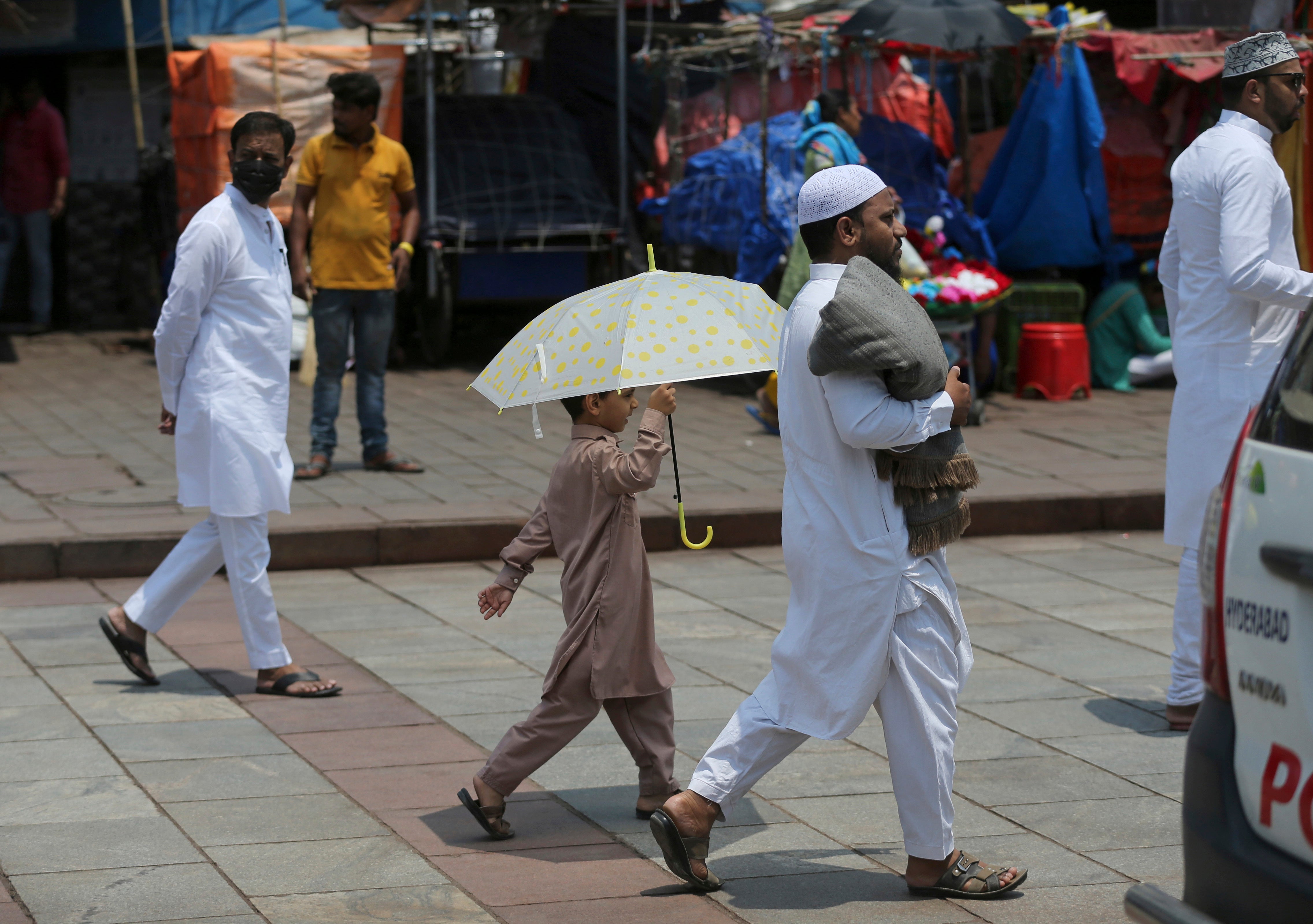 A boy holds an umbrella to protect himself from the heat in Hyderabad