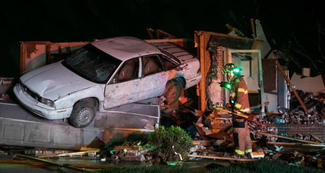 <p>A firefighter searches a home in Andover on Friday night after a tornado ripped through the area </p>