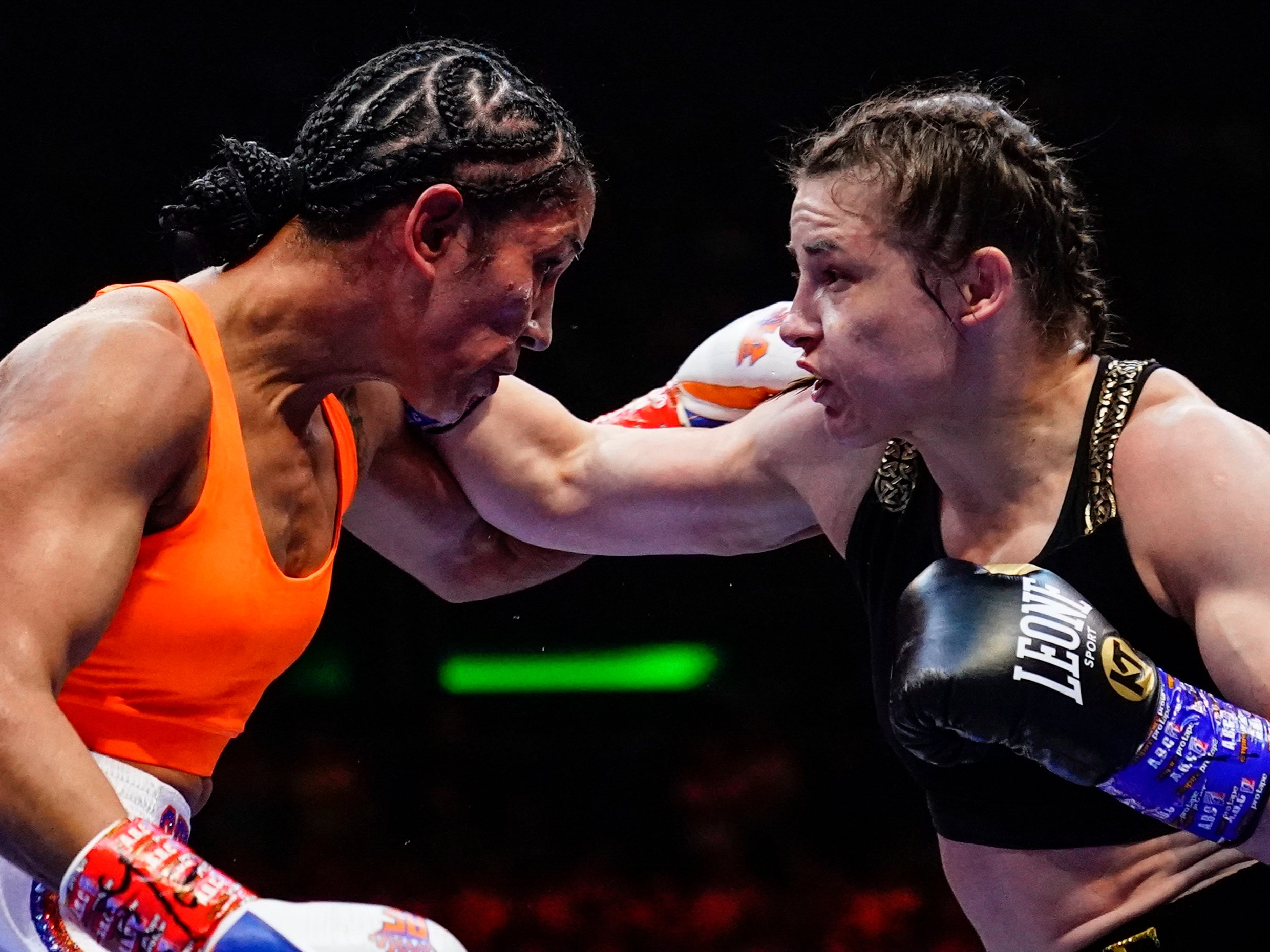 <p>Katie Taylor (right) remained unbeaten and retained her belts with the narrow win</p>