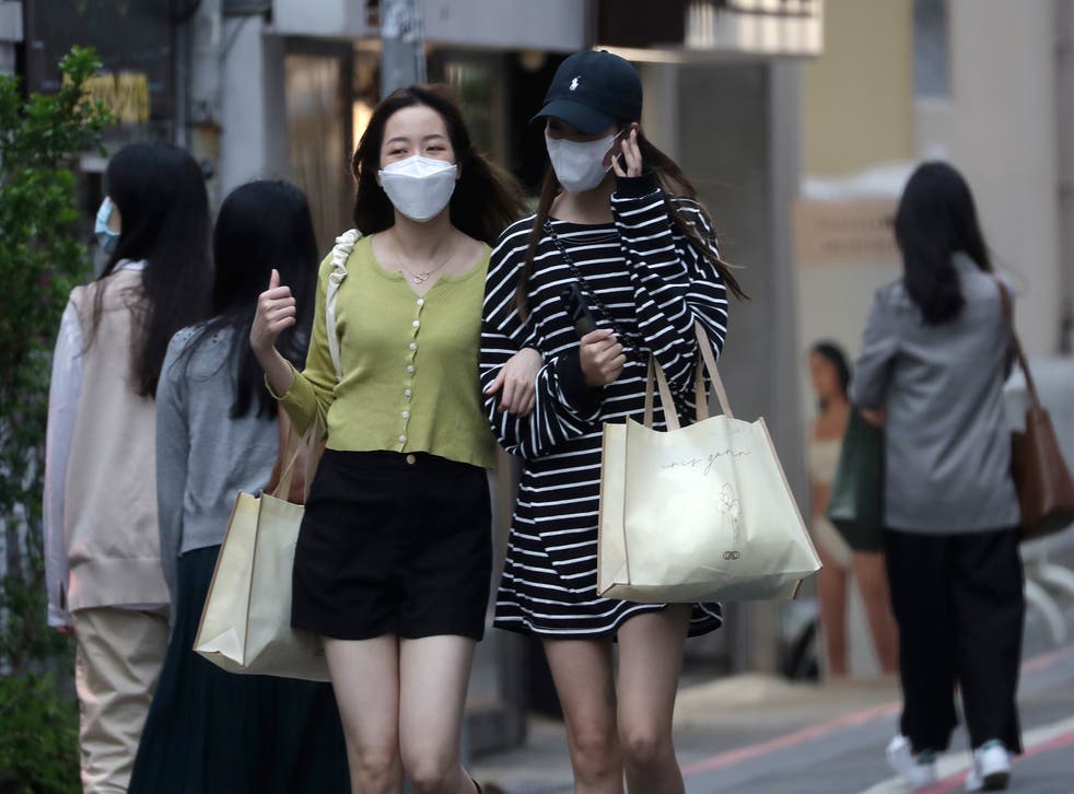 <p>Women wearing face masks to protect against the spread of Covid walk on a street in Taipei, Taiwan</p>